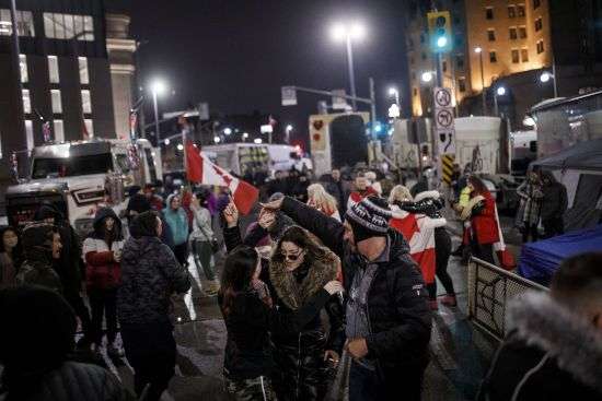 People dance during a protest against COVID-19 measures that has grown into a broader anti-government protest, in Ottawa, Ontario, Wednesday.
