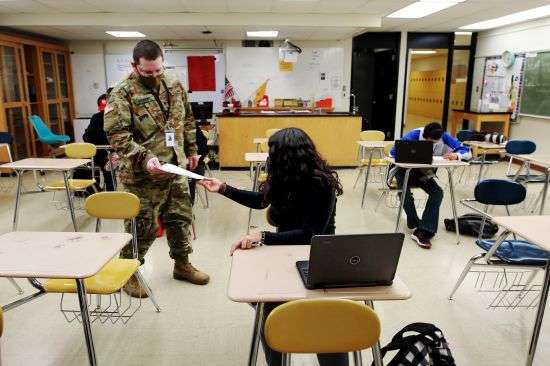 Substitute teacher and New Mexico Army National Guard specialist Michael Stockwell takes a geology assignment from Lilli Terrazas, 15, at Alamogordo High School, Tuesday, Feb. 8, 2022, in Alamogordo, N.M.
