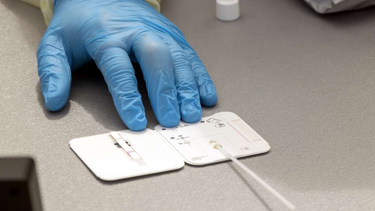 A worker holds a rapid COVID-19 antigen test on a table at a testing site at Rio Tinto Stadium in Sandy on Aug. 2, 2021. The Utah Department of Health on Monday reported 353 new COVID-19 cases and six additional deaths since Friday.