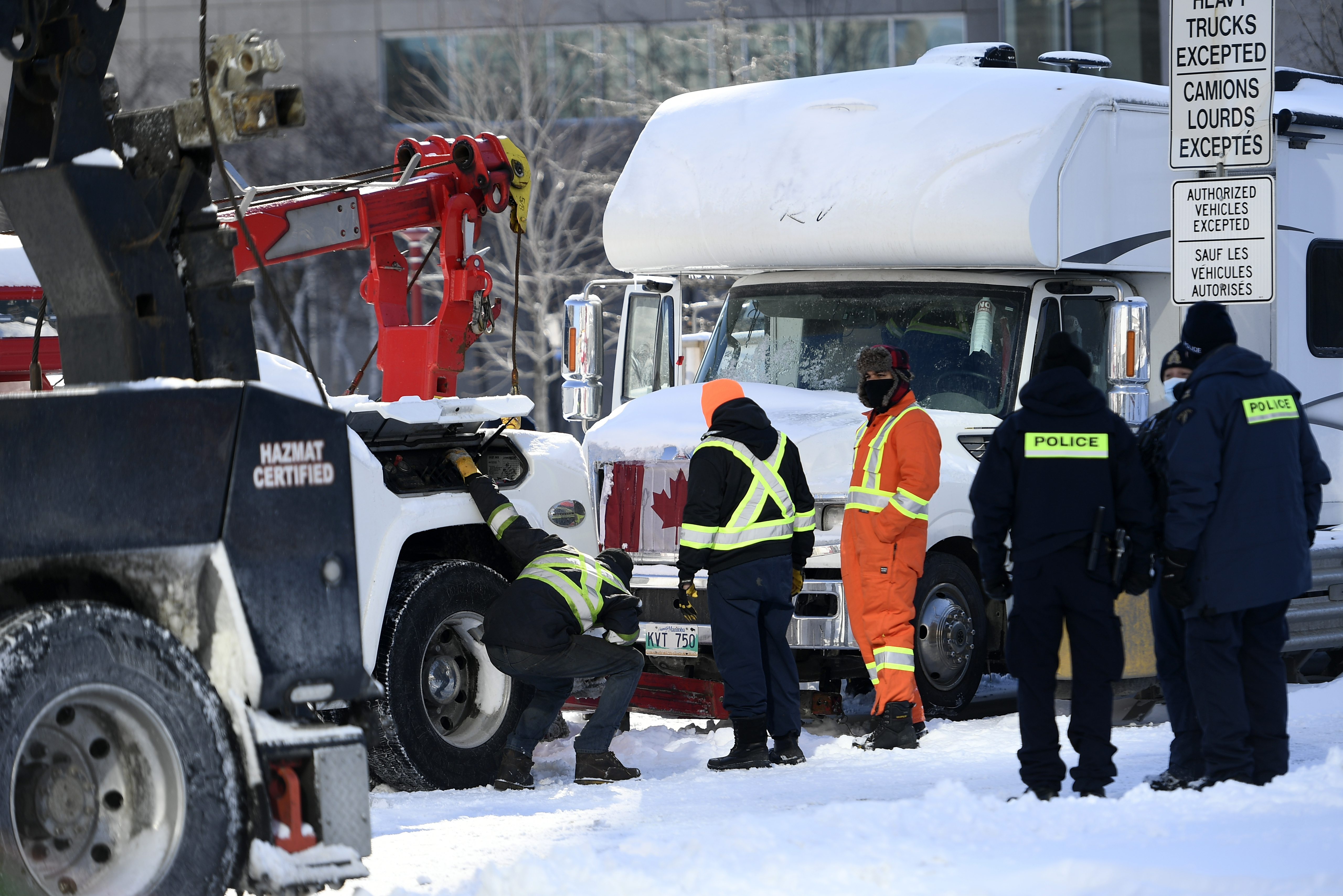 Police officers assist a tow operator to remove a truck from a blockade on Nicholas St. in Ottawa, on Friday.