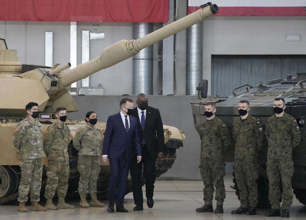 U.S. Defense Secretary Lloyd Austin, center, and Poland's Defense Minister Mariusz Blaszczak walk, during a visit to U.S. troops stationed at the Powidz Air Base, in Poland, Friday. Austin is in Europe for talks among fears in the West that Russia is planning to invade Ukraine, which borders NATO and European Union member Poland.