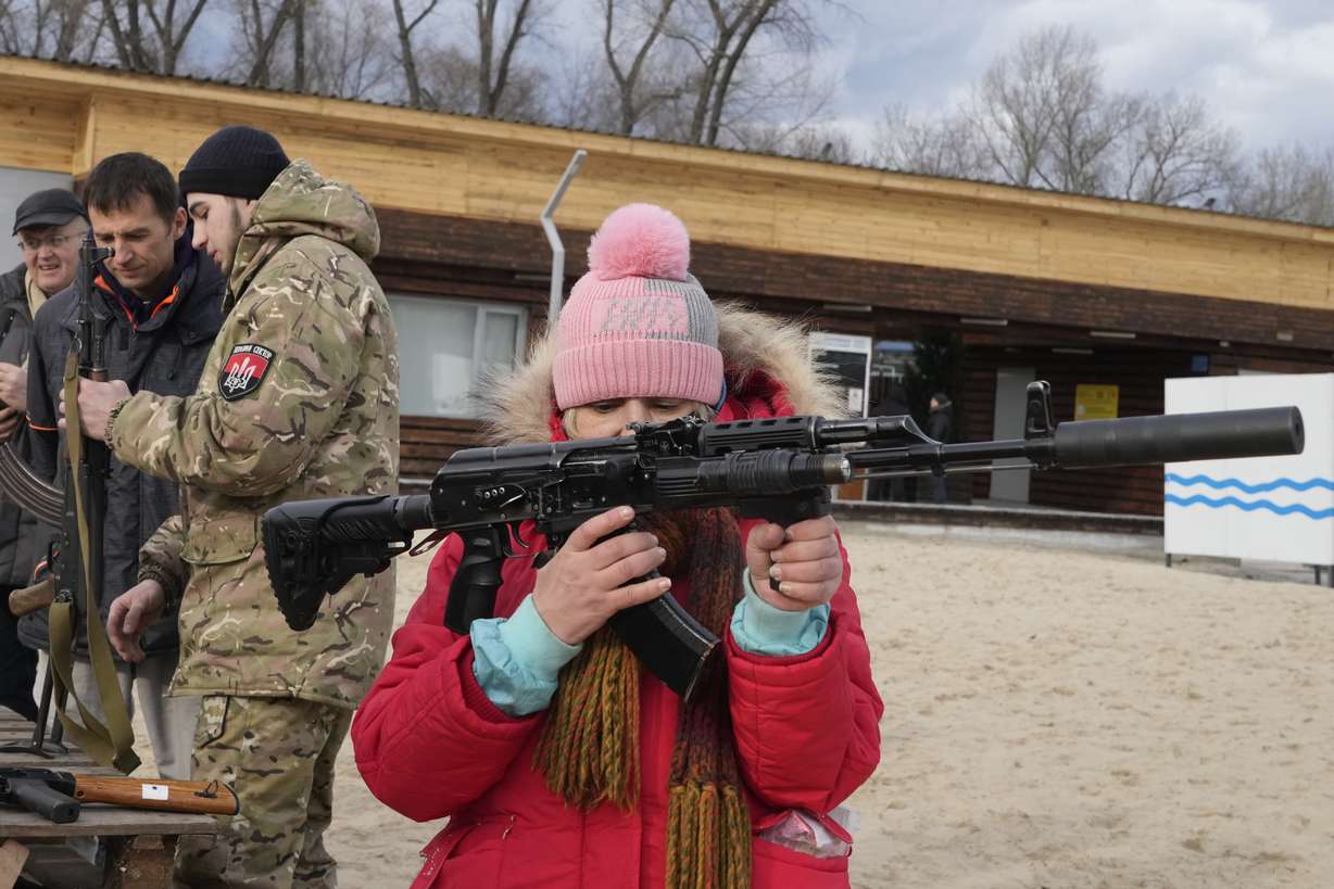 A woman holds a Kalashnikov assault rifle during a training of members of a Ukrainian far-right group train, in Kyiv, Ukraine, Sunday. Russia extended military drills near Ukraine's northern borders Sunday amid increased fears that two days of sustained shelling along the contact line between soldiers and Russa-backed separatists in eastern Ukraine could spark an invasion.