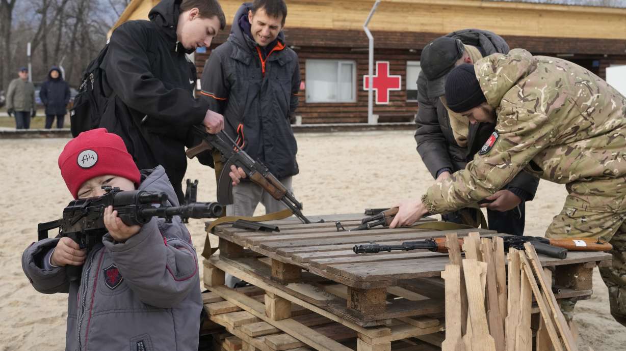 A boy plays with a weapon while an instructor shows a Kalashnikov assault rifle during a training of members of a Ukrainian far-right group train, in Kyiv, Ukraine, Sunday.