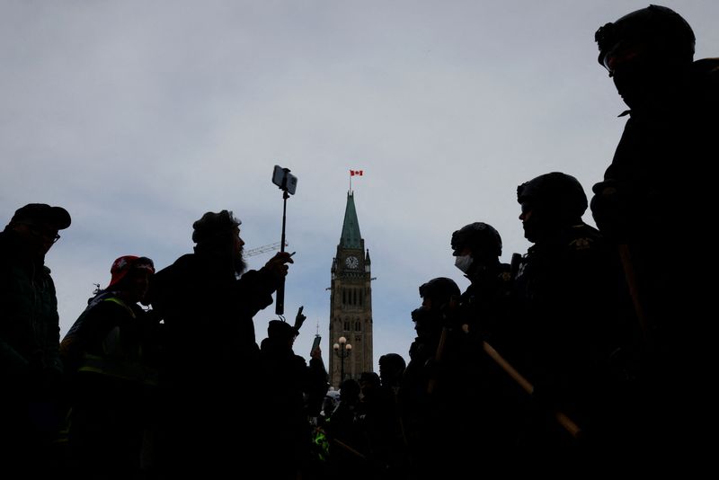 Canadian police officers stand guard in front of protesters, as they work to restore normality to the capital while trucks and demonstrators continue to occupy the downtown core for more than three weeks to protest against pandemic restrictions in Ottawa, Ontario, Canada, Feb. 19.
