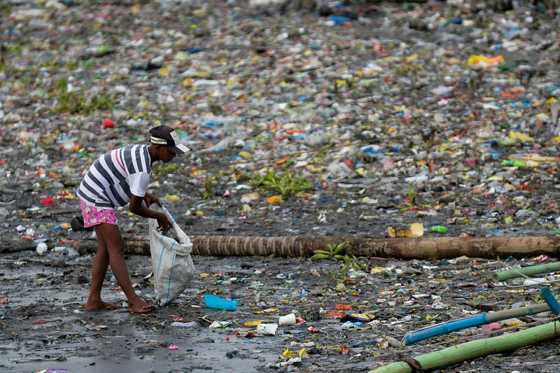 A woman picks up plastic cups along the riverbank of Pasig river, in Manila, Philippines, June 10, 2021. Three in four people worldwide want single-use plastics to be banned as soon as possible, according to a poll released on Tuesday.