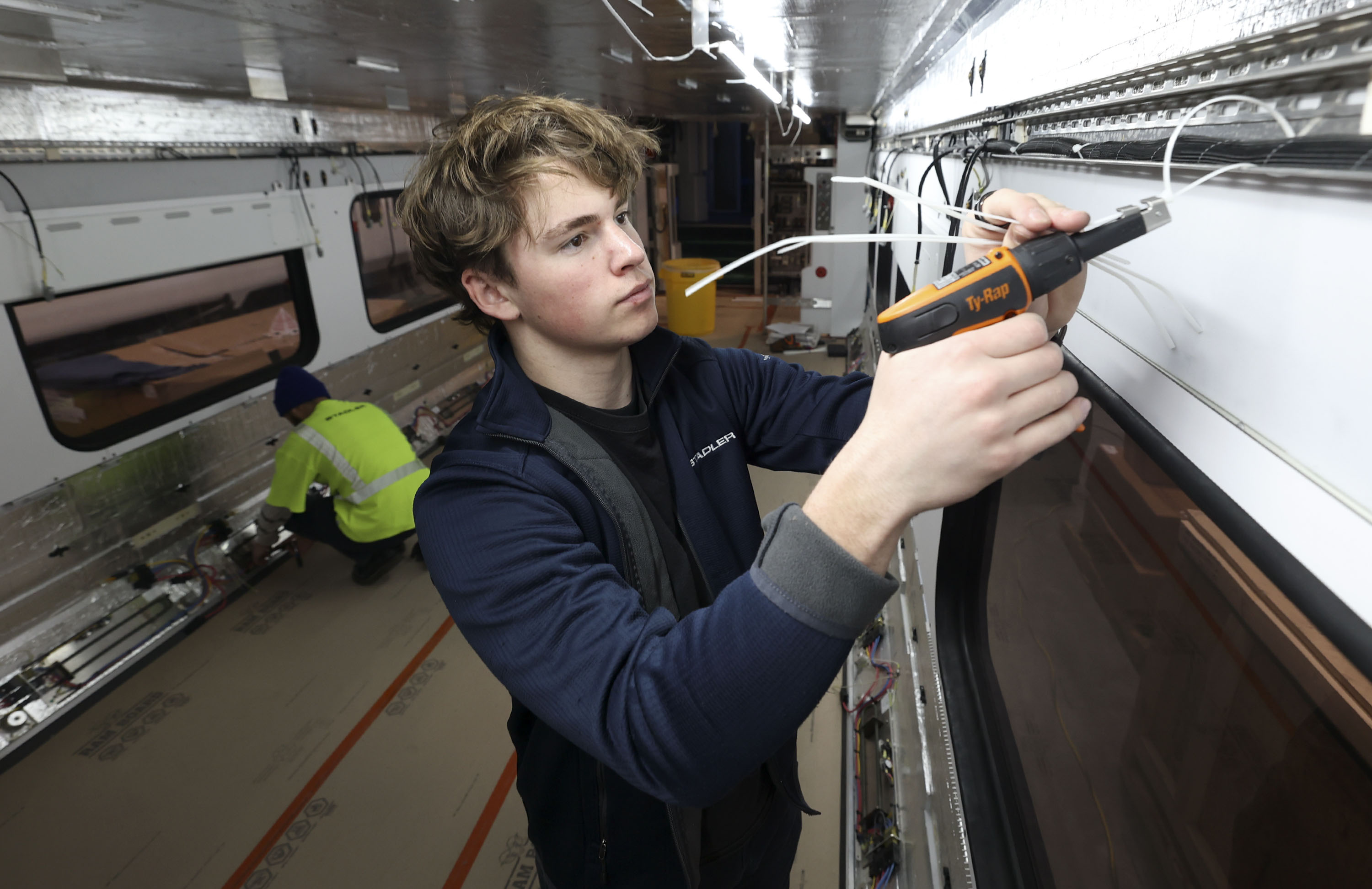 Jonathan Olsen, third year apprentice, attaches wiring on a train at Stadler Rail US in Salt Lake City on Wednesday, Feb. 23, 2022. Gov. Spencer Cox, Talent Ready Utah and the Utah State Board of Education announced the launch of the Utah Adopt-A-School initiative, which connects employers and students for work-based learning.