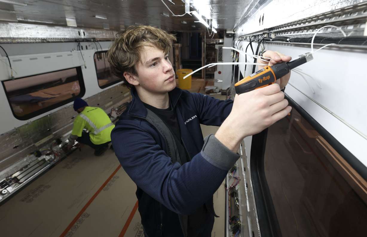 Jonathan Olsen, third year apprentice, attaches wiring on a train at Stadler Rail US in Salt Lake City on Wednesday, Feb. 23, 2022. Gov. Spencer Cox, Talent Ready Utah and the Utah State Board of Education announced the launch of the Utah Adopt-A-School initiative, which connects employers and students for work-based learning.