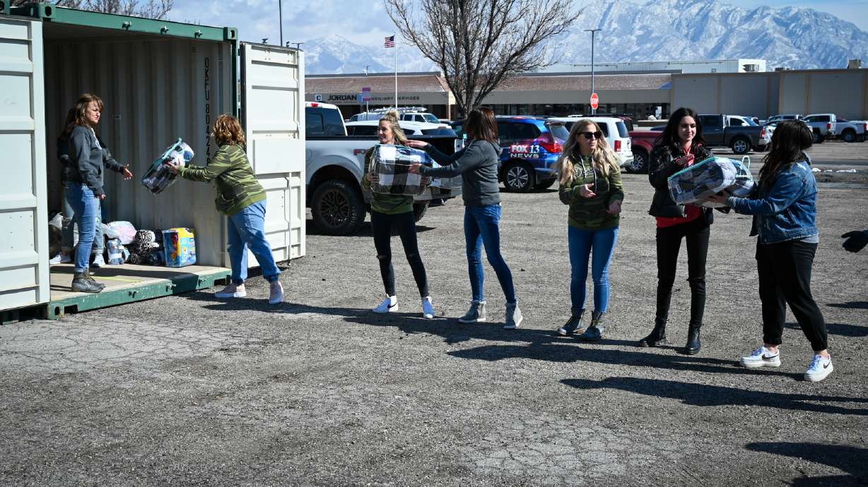 Beddy's employees pass down bedding sets to be picked up by families in need at the Jordan School District auxiliary services parking lot in West Jordan on Thursday. The Jordan Education Foundation partnered with Beddy's, a West Jordan company that produces one-piece zipper bedding sets, to donate 150 bedding sets to students and families as part of the foundation's “Bed‘R Homes for Kids” campaign.