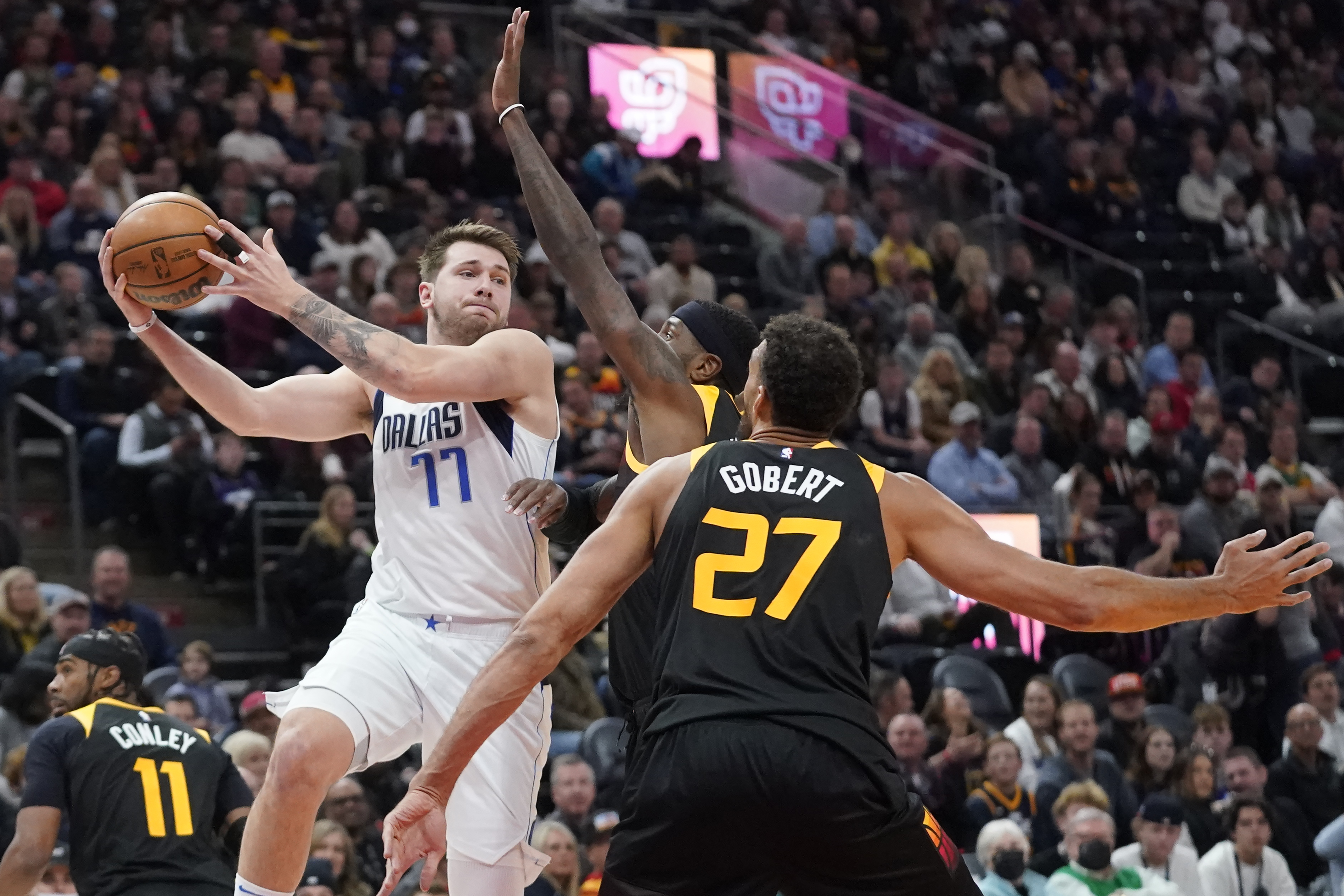 Dallas Mavericks guard Luka Doncic (77) passes the ball as Utah Jazz forward Royce O'Neale, back right, and center Rudy Gobert (27) defend during the first half of an NBA basketball game Friday, Feb. 25, 2022, in Salt Lake City.