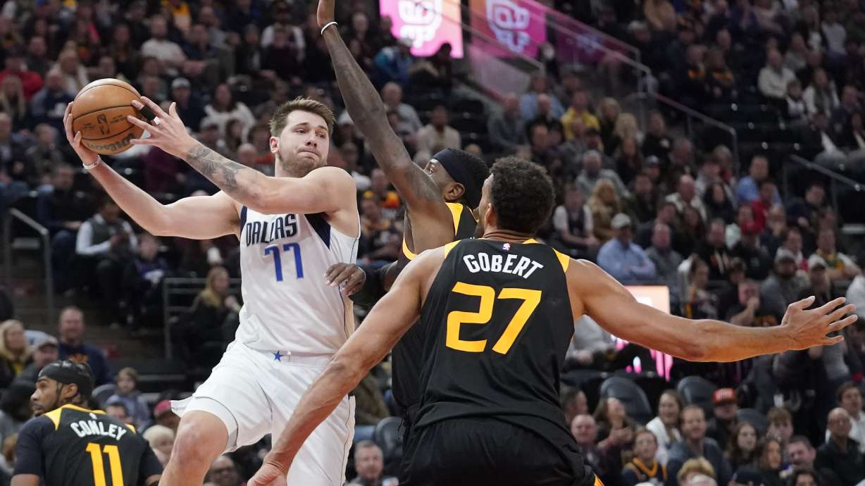Dallas Mavericks guard Luka Doncic (77) passes the ball as Utah Jazz forward Royce O'Neale, back right, and center Rudy Gobert (27) defend during the first half of an NBA basketball game Friday, Feb. 25, 2022, in Salt Lake City.