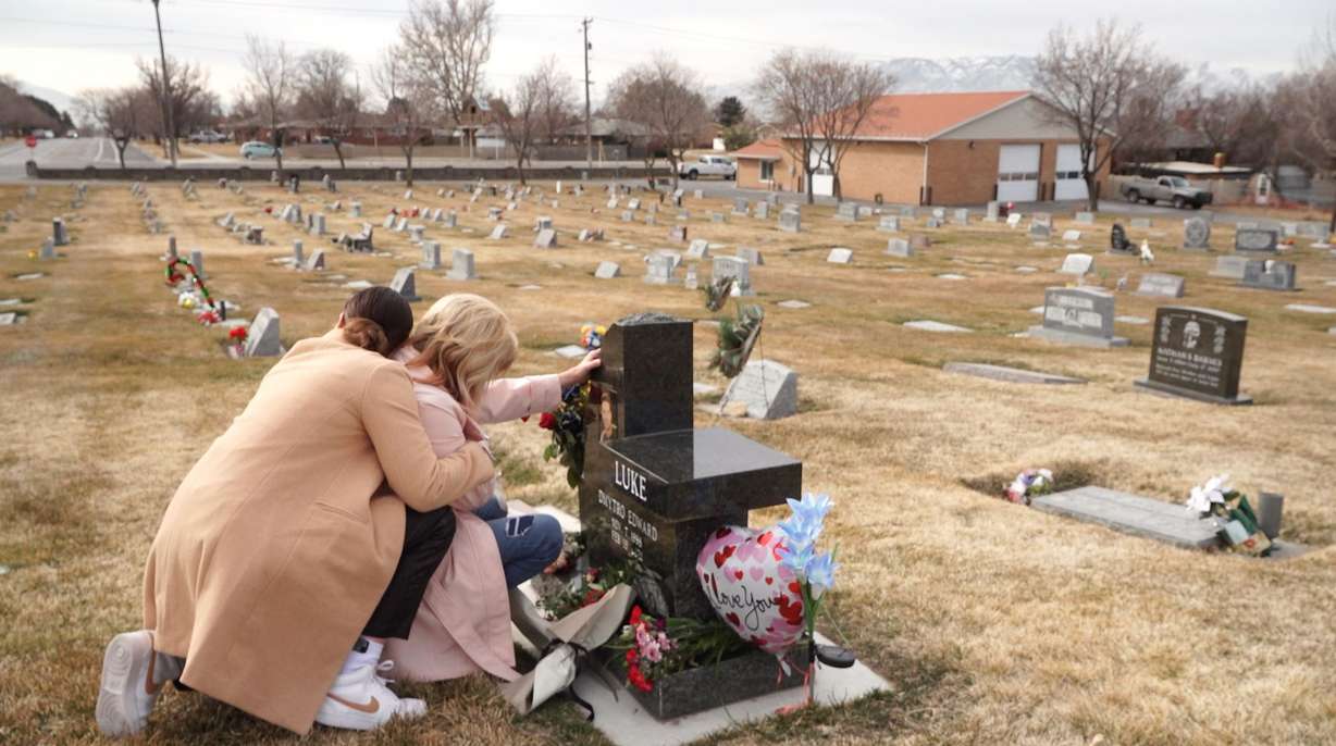 Ruth Lee hugs her mother, Lee-Ann Luke, as she cries kneeling at the headstone of her son Troy Luke. He was 22 years old when he died last February after overdosing on what he thought was an oxycodone. His family learned after his passing that the pill he took had been laced with fentanyl.