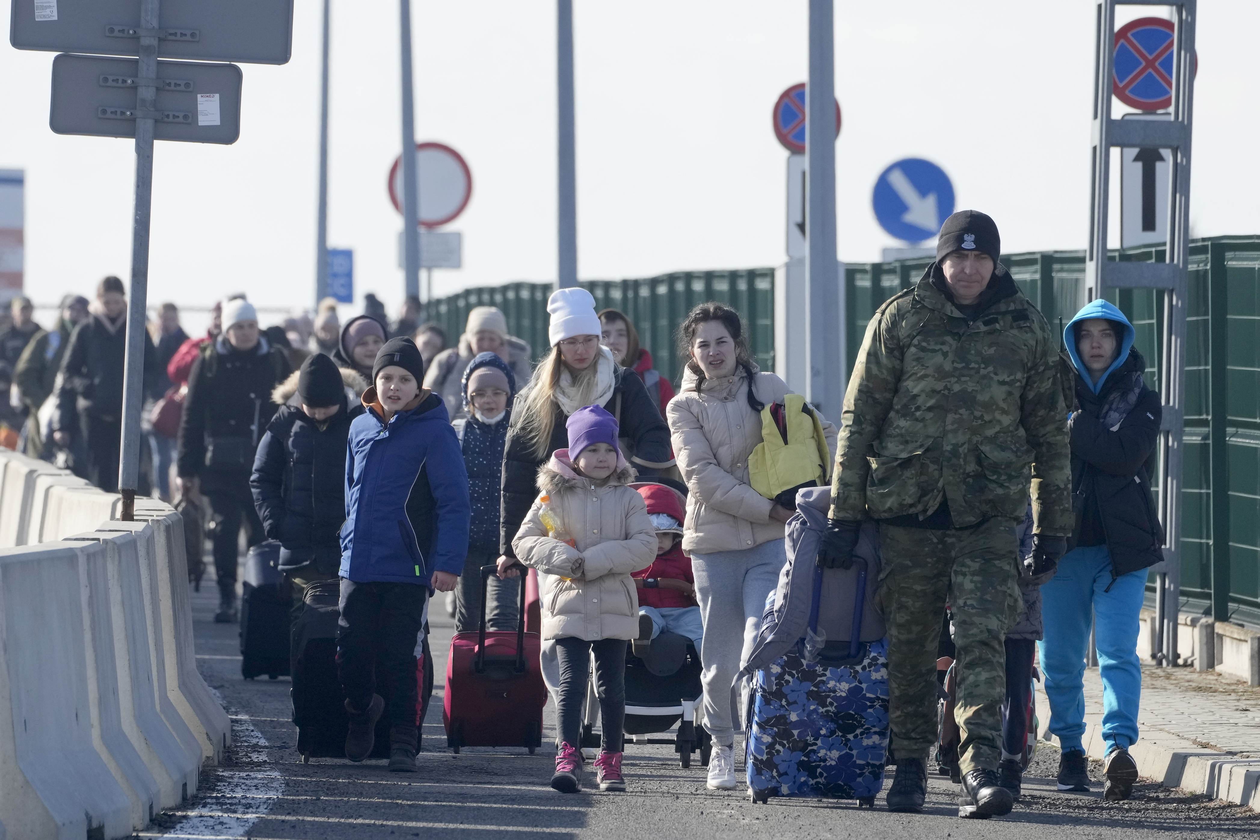 A Polish border guard assists refugees from Ukraine as they arrive to Poland at the Korczowa border crossing, Poland, Saturday.