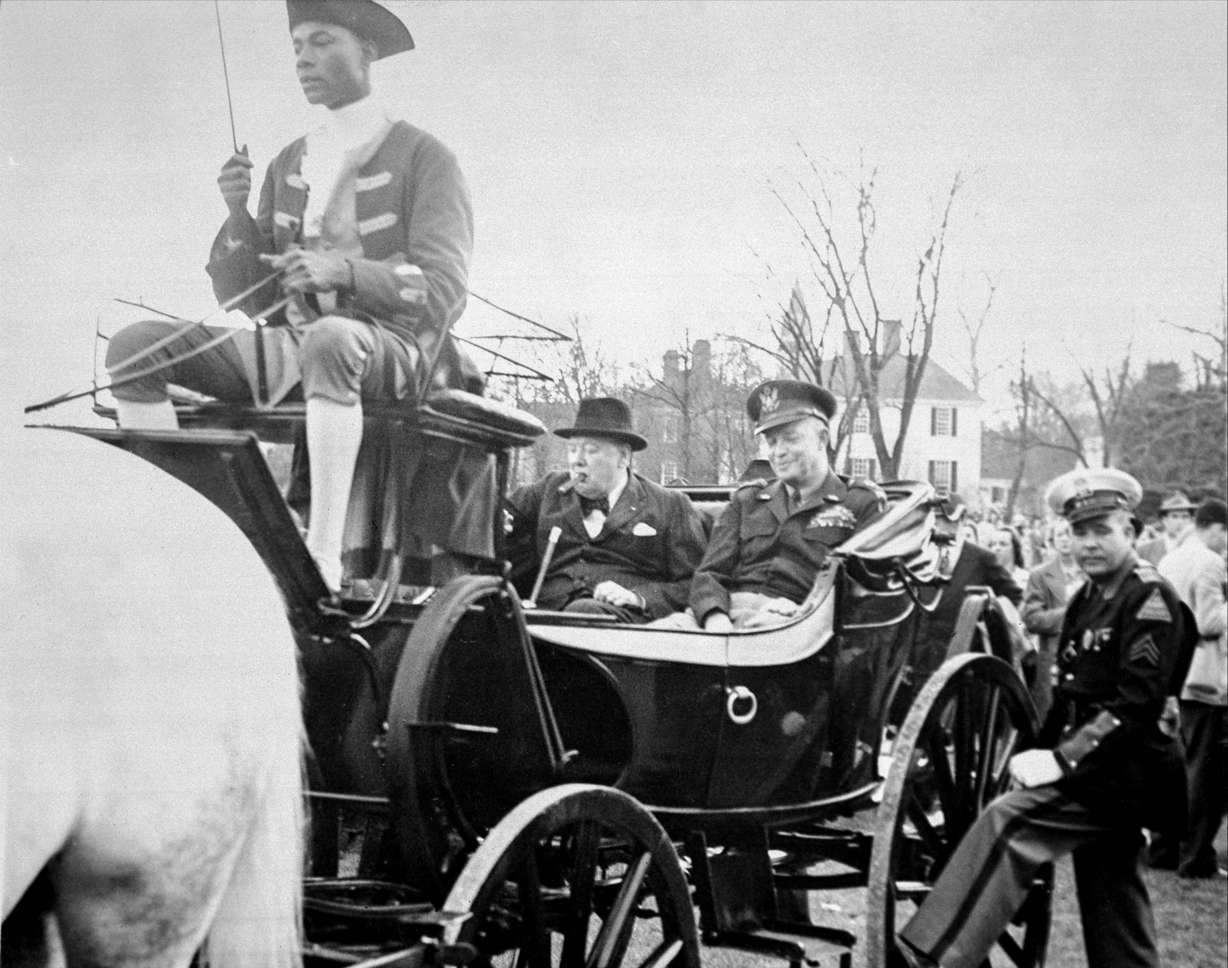 Colonial Williamsburg coachman Benjamin Spraggins sits atop a carriage holding former British Prime Minister Winston Churchill and then-Gen. Dwight D. Eisenhower in Williamsburg, Va., on March 8, 1946. The living history museum is honoring Spraggins, a Black man who worked at the museum during the era of segregation, by naming a new carriage after him. The tribute is part of the museum’s ongoing reckoning over race and its past storytelling about the country’s origins and the role of Black Americans.