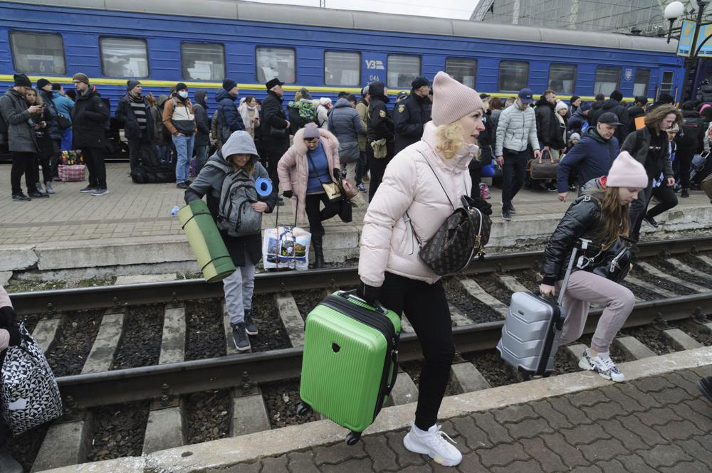 People gather to catch a train and leave Ukraine for neighboring countries at the railway station in Lviv, western Ukraine, Saturday. The U.N. refugee agency says nearly 120,000 people have so far fled Ukraine into neighboring countries in the wake of the Russian invasion. 