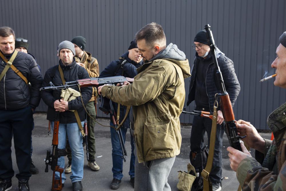 Civilian Members of a territorial defense unit fit their weapons to repel the Russian attacking forces in Kyiv, Ukraine, Saturday. The United States, European Union and the United Kingdom on Saturday agreed to put in place crippling sanctions on the Russian financial sector.