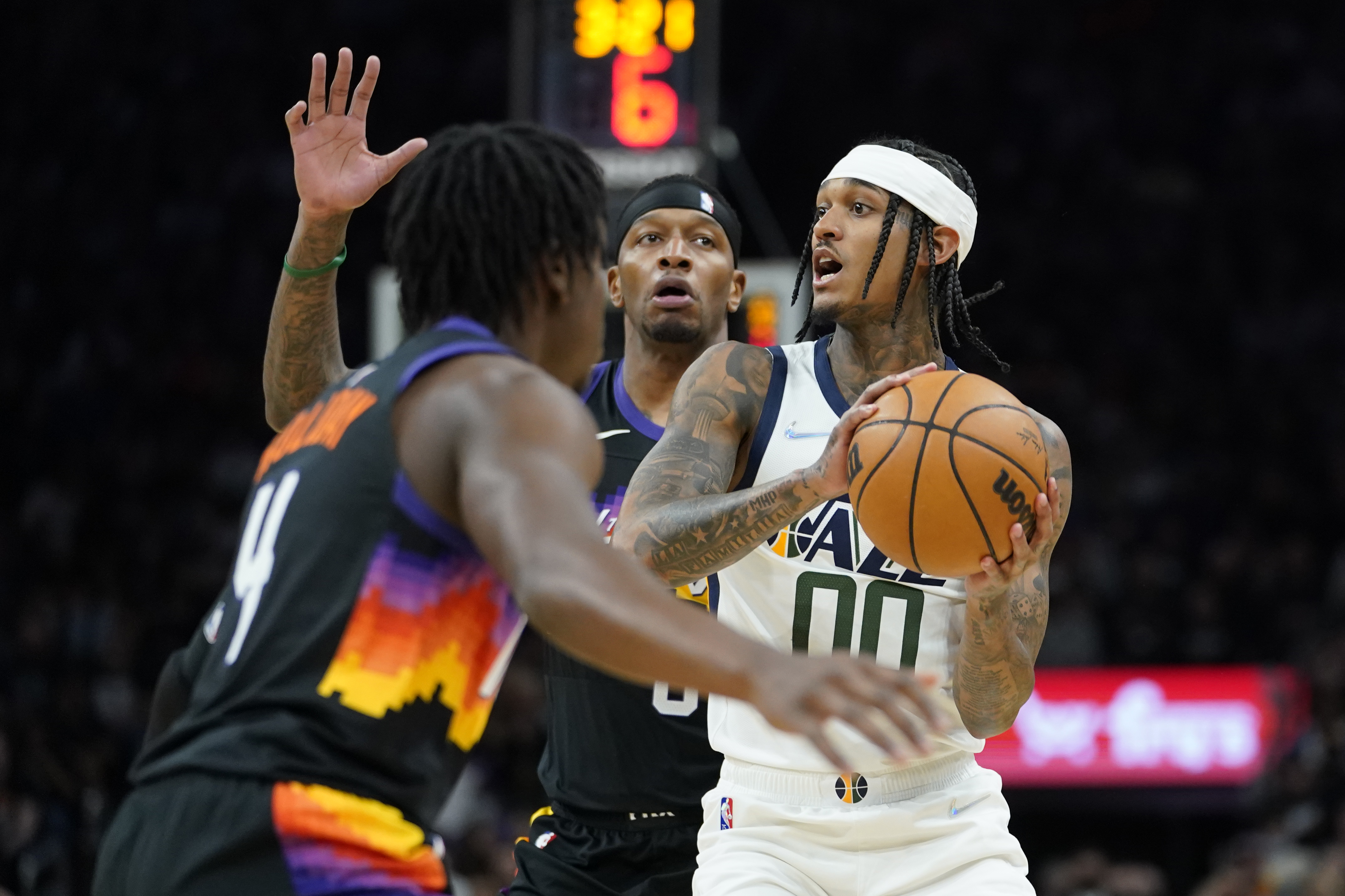 Utah Jazz guard Jordan Clarkson (00) looks to pass under pressure from Phoenix Suns forward Torrey Craig, center, during the first half of an NBA basketball game, Sunday, Feb. 27, 2022, in Phoenix.