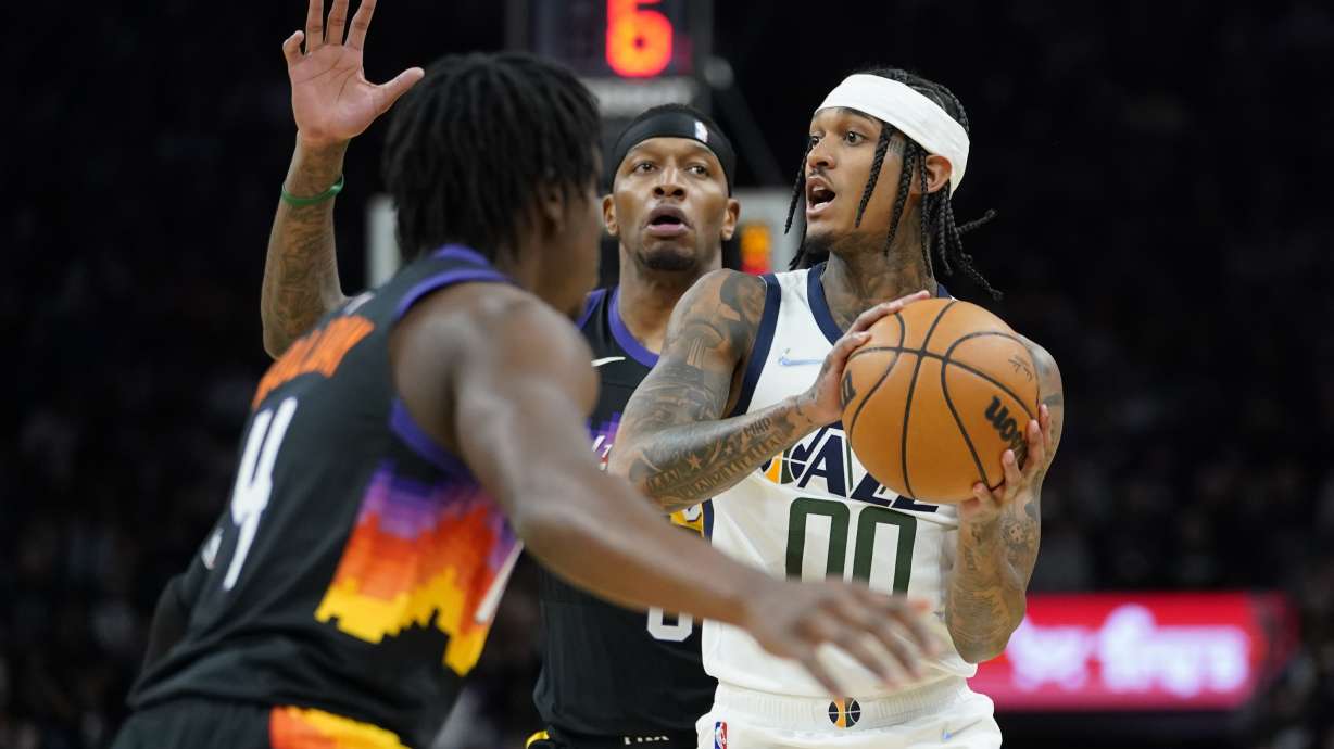 Utah Jazz guard Jordan Clarkson (00) looks to pass under pressure from Phoenix Suns forward Torrey Craig, center, during the first half of an NBA basketball game, Sunday, Feb. 27, 2022, in Phoenix.
