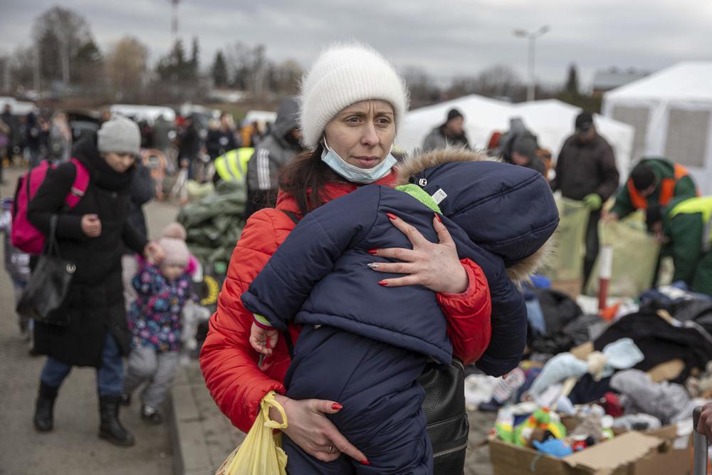 A woman carries her child as she arrives at the Medyka border crossing after fleeing from the Ukraine, in Poland, Monday. The head of the United Nations refugee agency says more than a half a million people had fled Ukraine since Russia’s invasion on Thursday.