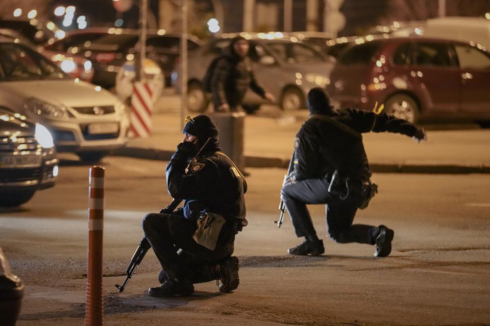 Ukrainian police rush a traveler to the railway station terminal during an airstrike alarm in Kyiv, Ukraine, Monday. Explosions and gunfire that have disrupted life since the invasion began last week appeared to subside around Kyiv overnight, as Ukrainian and Russian delegations met Monday on Ukraine's border with Belarus.