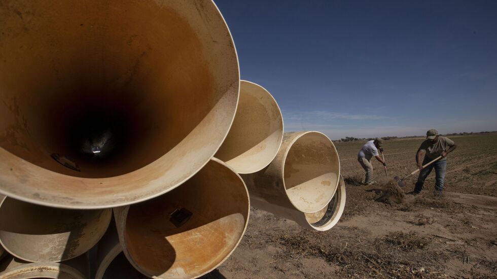 Austin Woodward, left, and Robert Salais, right, prepare to lay gated pipe that will irrigate water to farmer Matt Heimerich’s winter wheat fields in Crowley County outside of the town of Olney Springs, Colo., on Oct. 21, 2020. Utah and the rest of the West are reeling through the effects of a warming climate firsthand, a new report says.