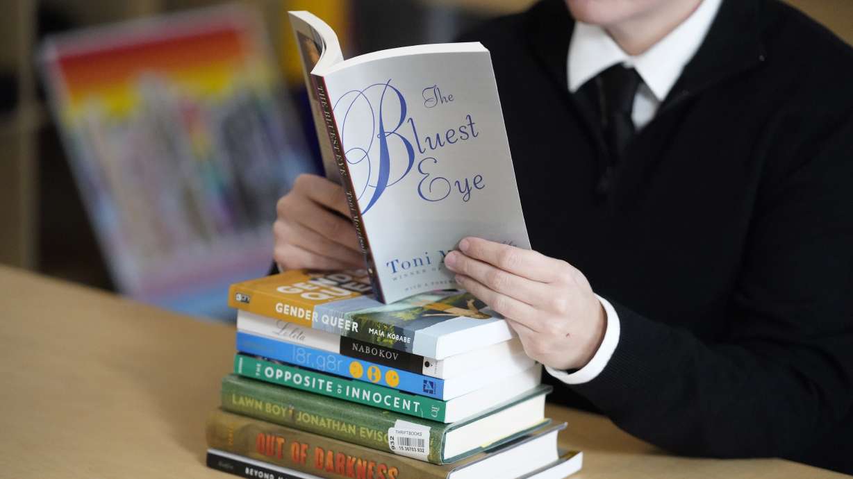 Amanda Darrow poses with books that have been the subject of complaints from parents in Salt Lake City on Dec. 16, 2021. A Utah House committee on Tuesday gave the OK to a measure proposing new rules on removal of books from school libraries.