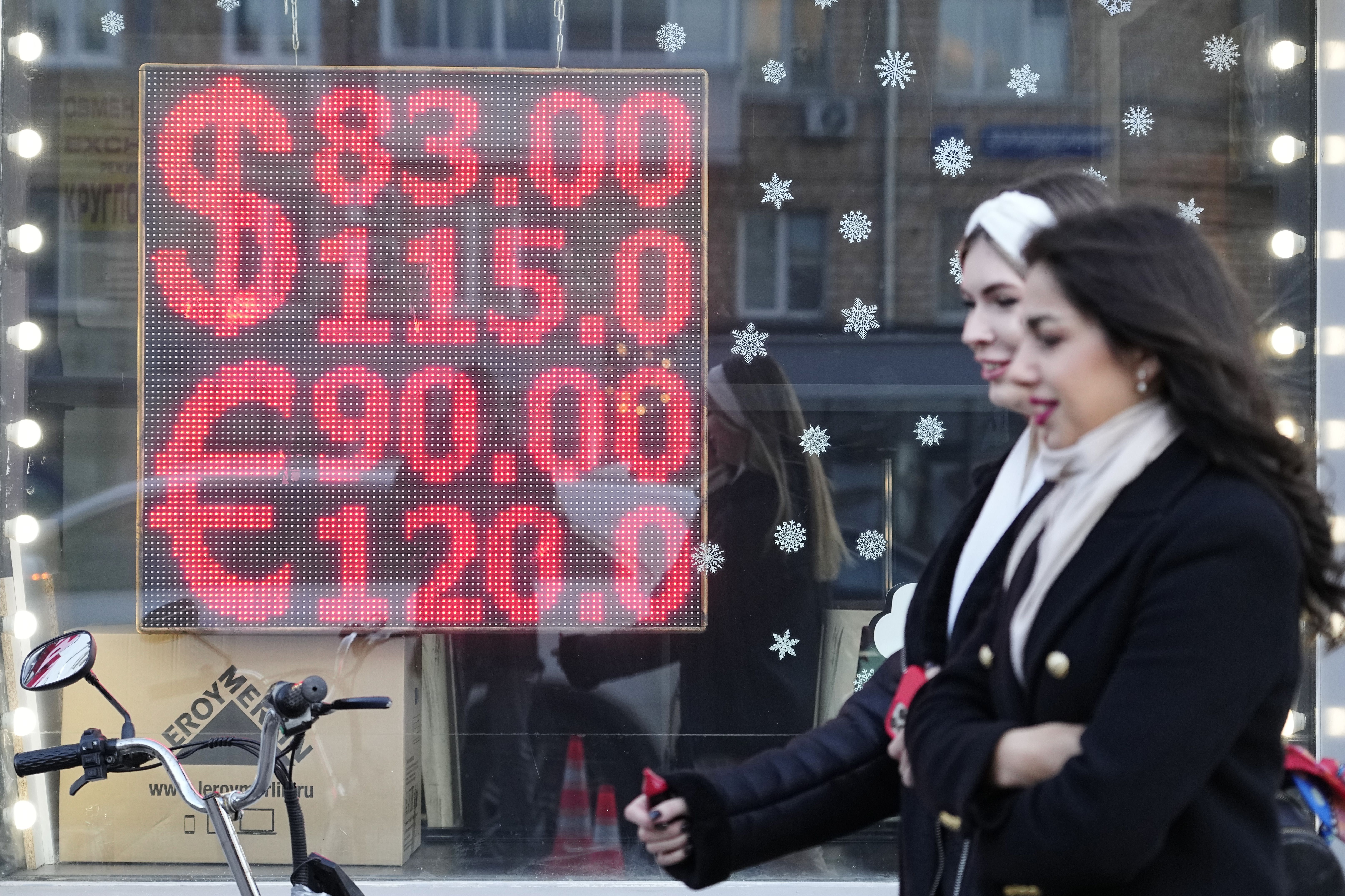 People walk past a currency exchange office screen displaying the exchange rates of U.S. dollar and euro to Russian rubles in Moscow’s downtown on Monday.