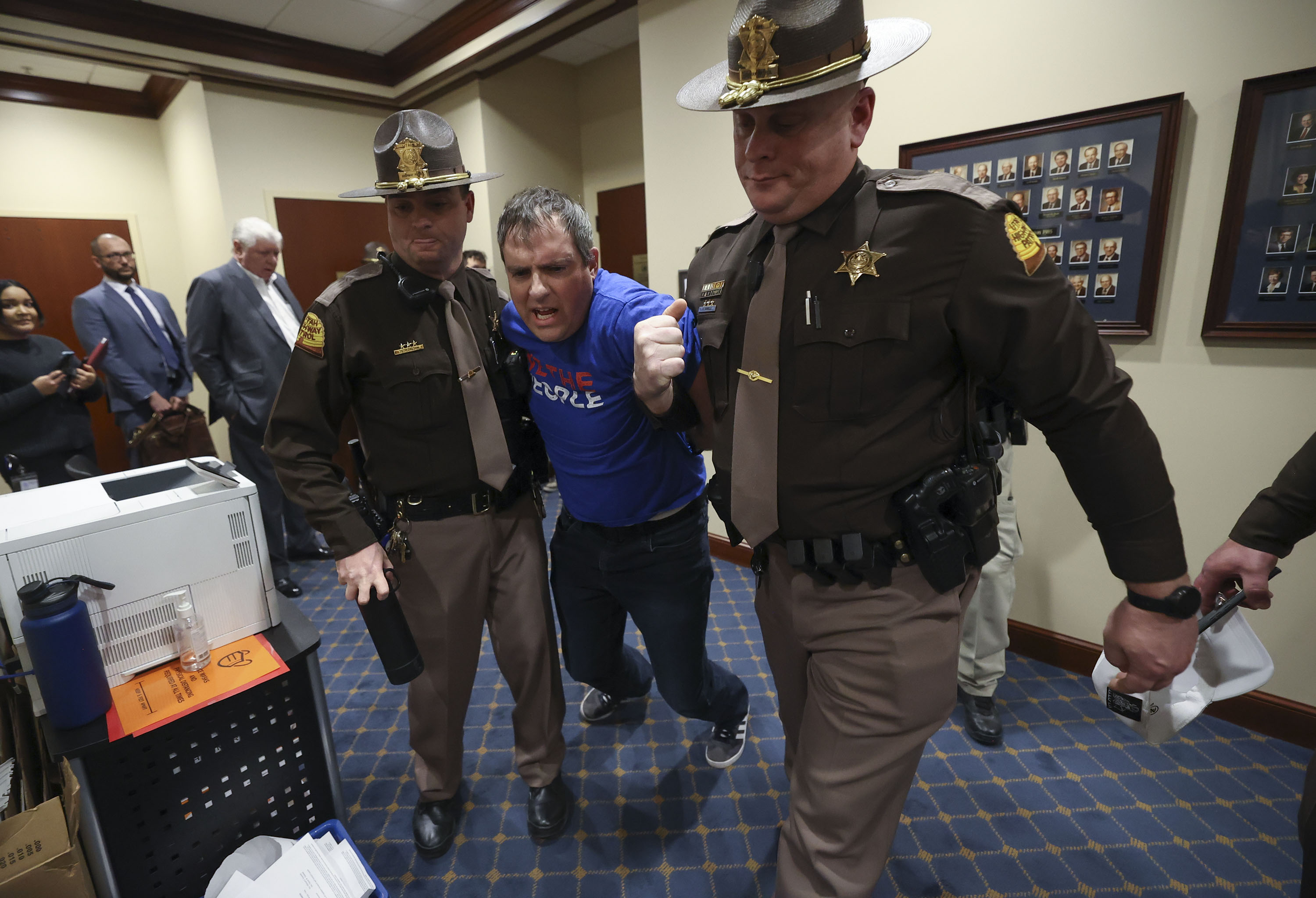 Utah Highway Patrol troopers take a man into custody for violating committee meeting rules by failing to cover up a political shirt, before the start of discussion on vaccine passport amendments during a committee meeting at the state Capitol on Tuesday.