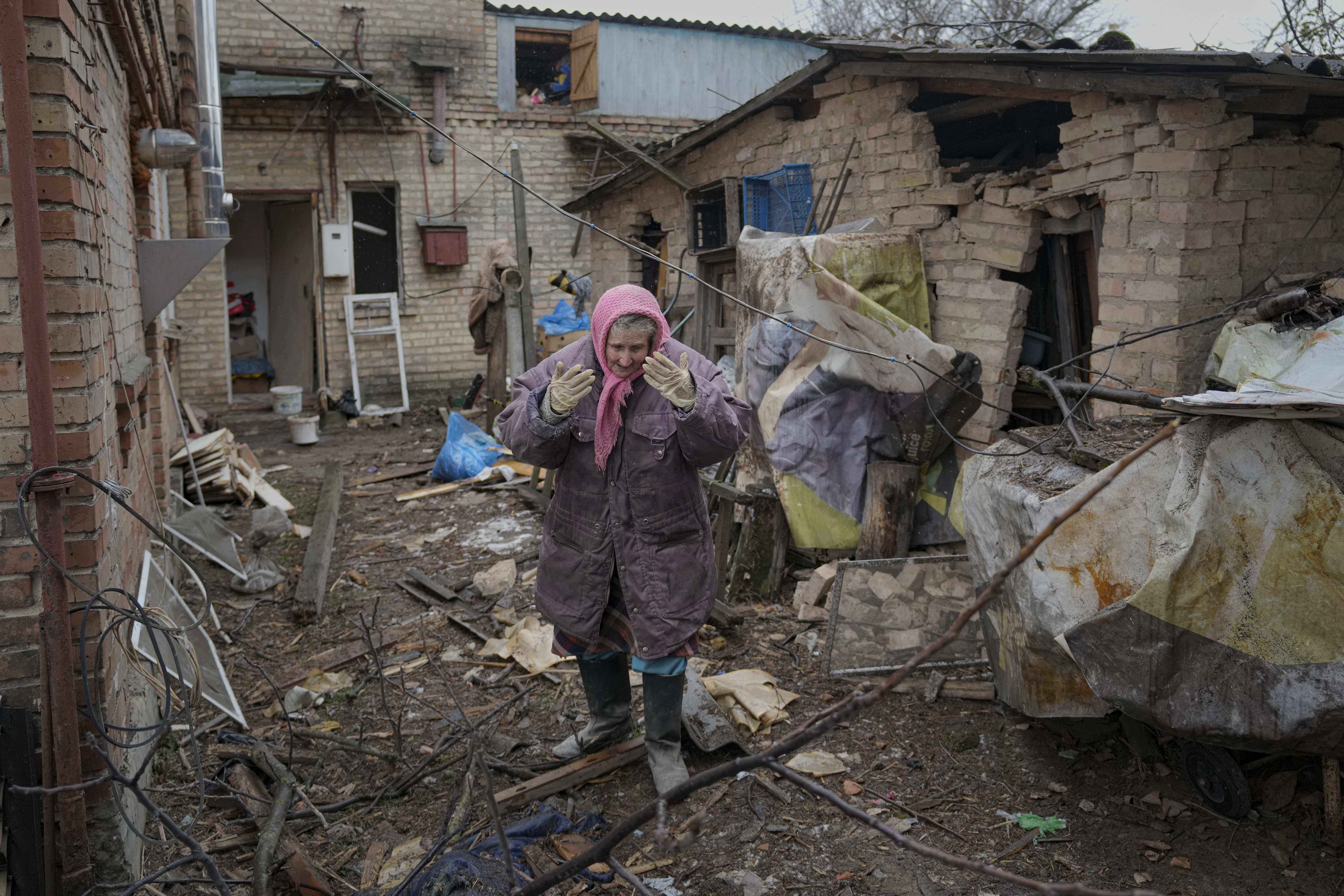 A woman is overwhelmed by emotion in the backyard of a house damaged by a Russian airstrike, according to locals, in Gorenka, outside the capital Kyiv, Ukraine, Wednesday. Russia's attack on Ukraine has sent shockwaves around the globe, and many people are feeling stress, anxiety and fear.