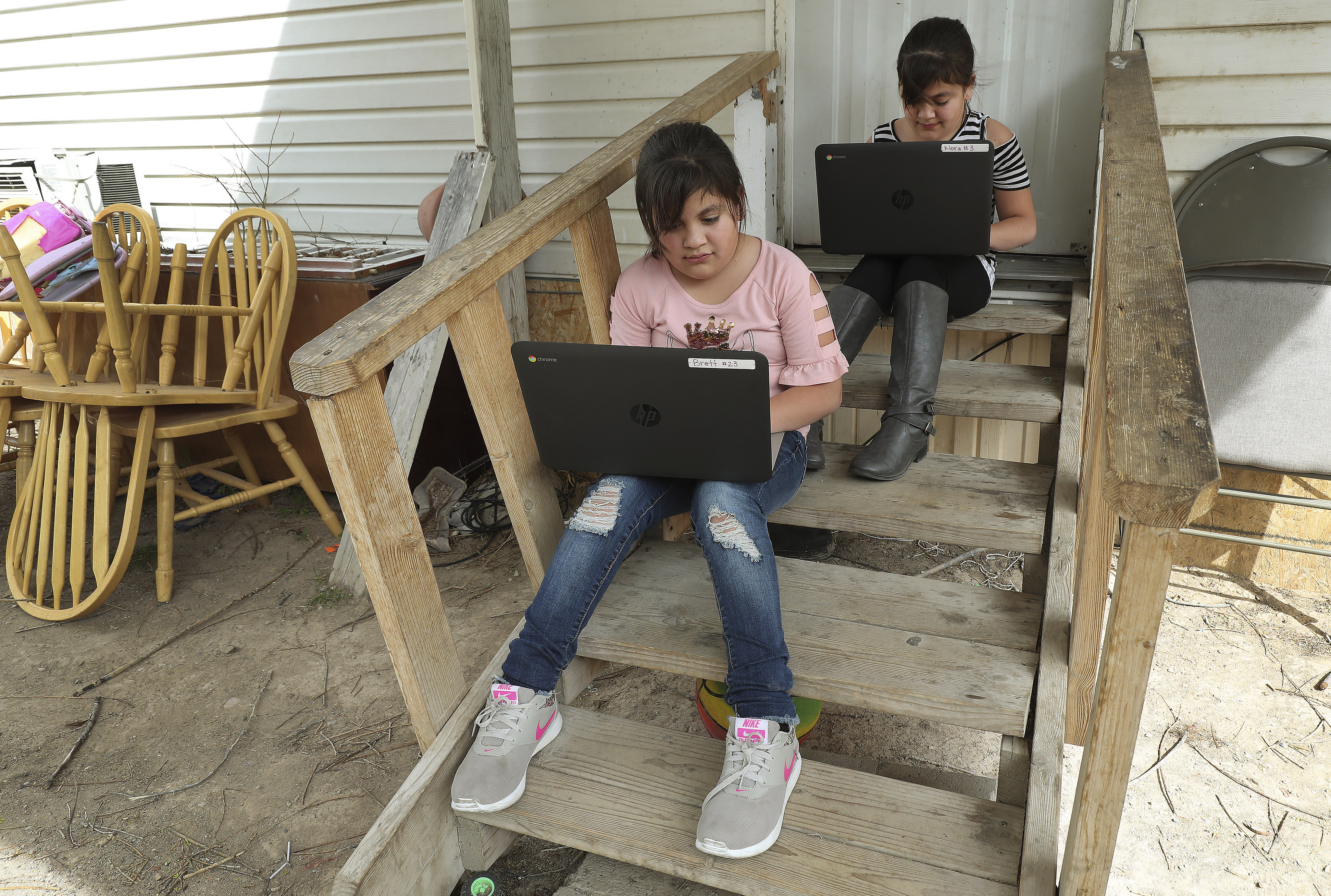 Jazmin Rascon and twin sister Judith work on their laptops on the front steps of their home in Delta on April 8, 2020. The Utah Broadband Center is asking Utahns to report their internet speeds at home, work or wherever they are online for a campaign to map areas with low speeds or no internet connection in the state.