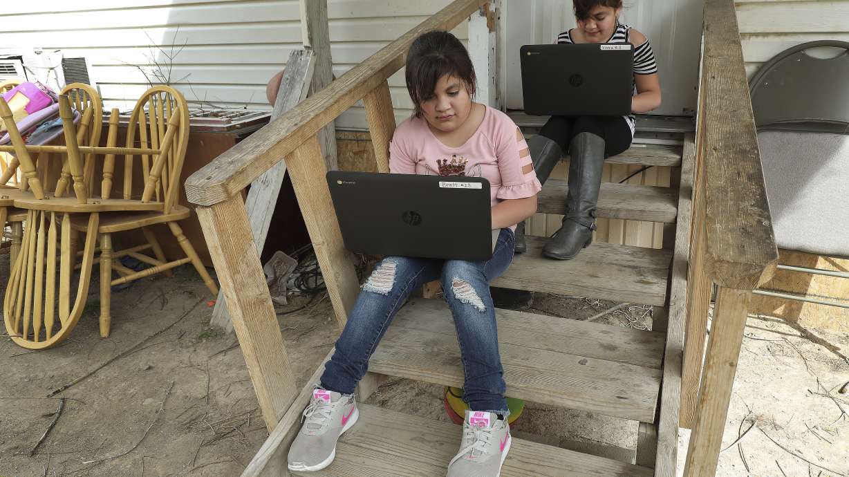 Jazmin Rascon and twin sister Judith work on their laptops on the front steps of their home in Delta on April 8, 2020. The Utah Broadband Center is asking Utahns to report their internet speeds at home, work or wherever they are online for a campaign to map areas with low speeds or no internet connection in the state.