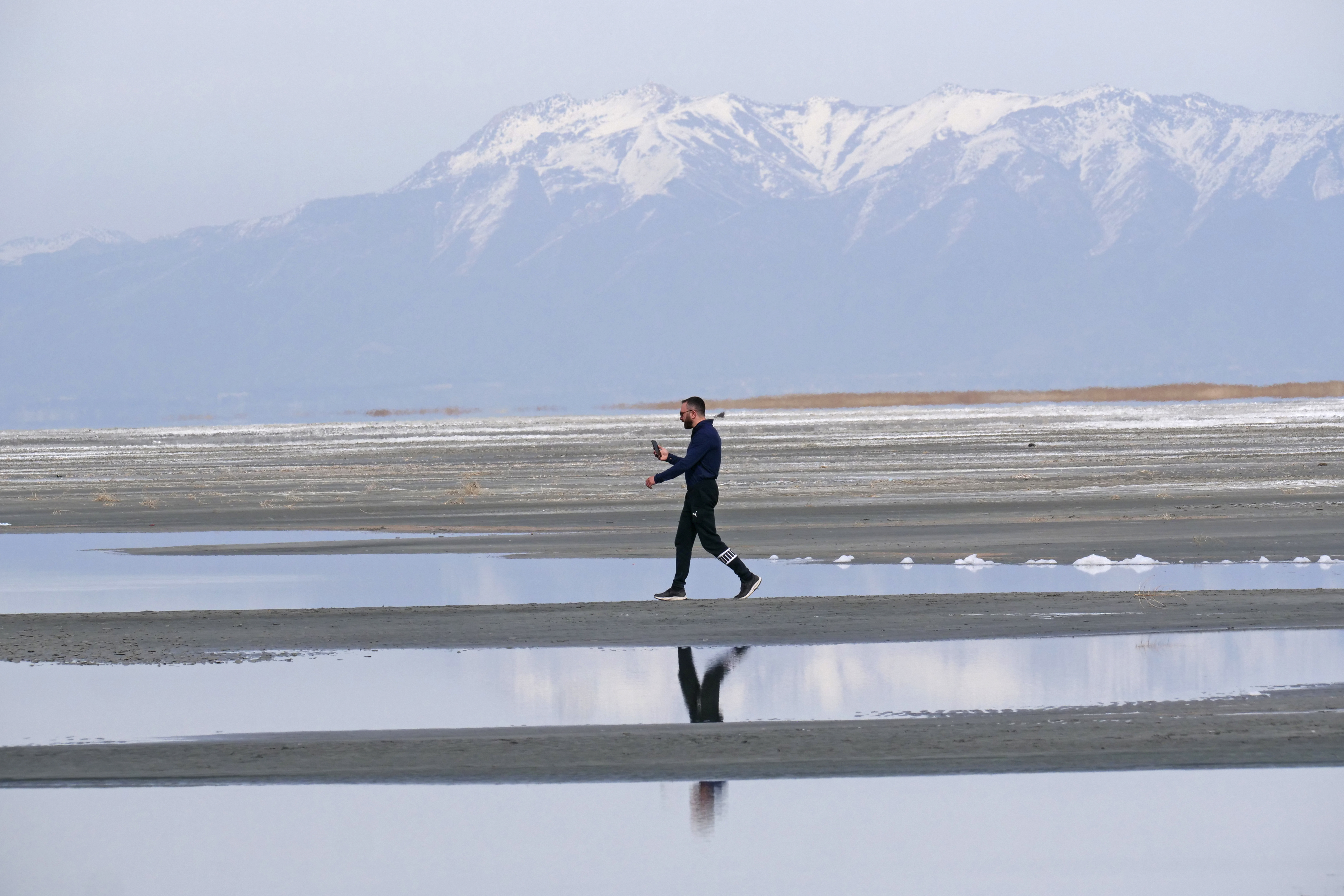 Ruben Gyoeltsyan walks across a sand bar at the receding edge of the Great Salt Lake, March 3, near Salt Lake City. Utah's Speaker of the House Brad Wilson, R-Kaysville, says he's bringing back the Great Salt Lake Summit in October.