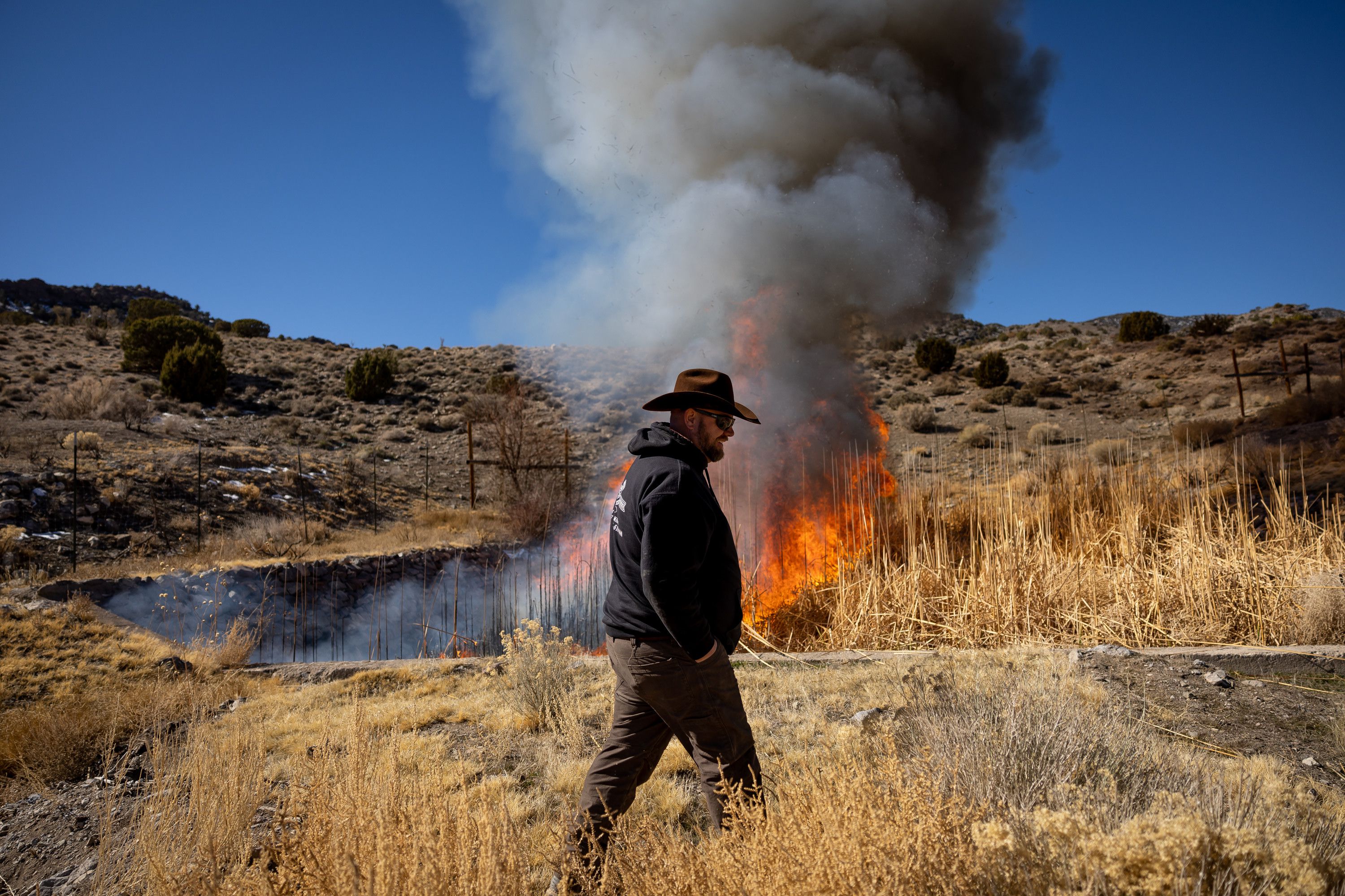 Mark Wintch watches after setting ablaze the weeds choking the natural spring that feeds his cattle ranch in the Wah Wah Valley, a remote part of Beaver County, on Feb. 18. Rural areas of Utah are facing a dire water shortage and it is setting the blueprint for a western desert conflict.