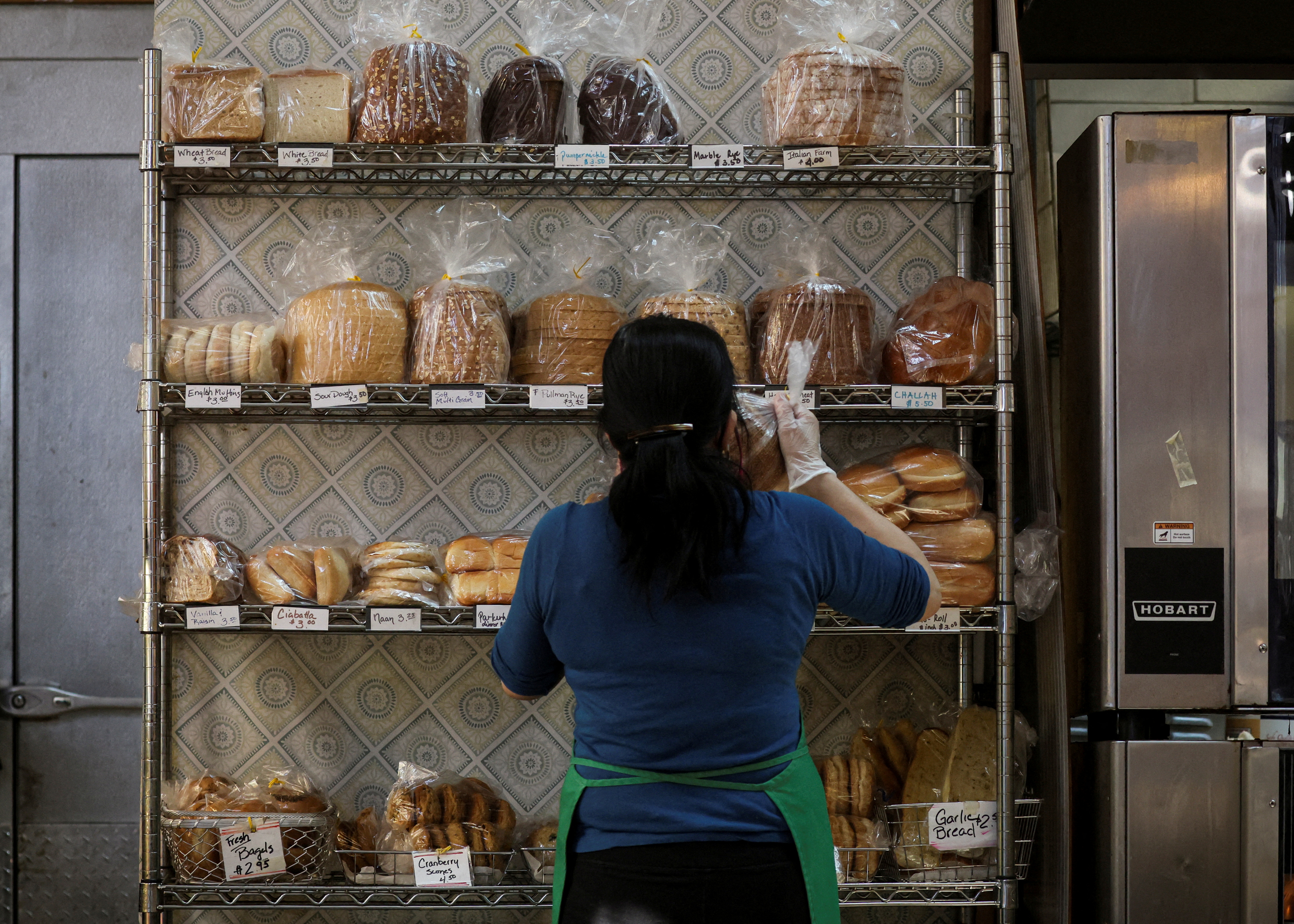 A baker stocks shelves with bread at the Eastern Market in Washington, Feb. 11. Russia's invasion of Ukraine, one of the world's breadbasket nations, has driven wheat prices to 14-year highs, forcing bread consumers to eat the cost.