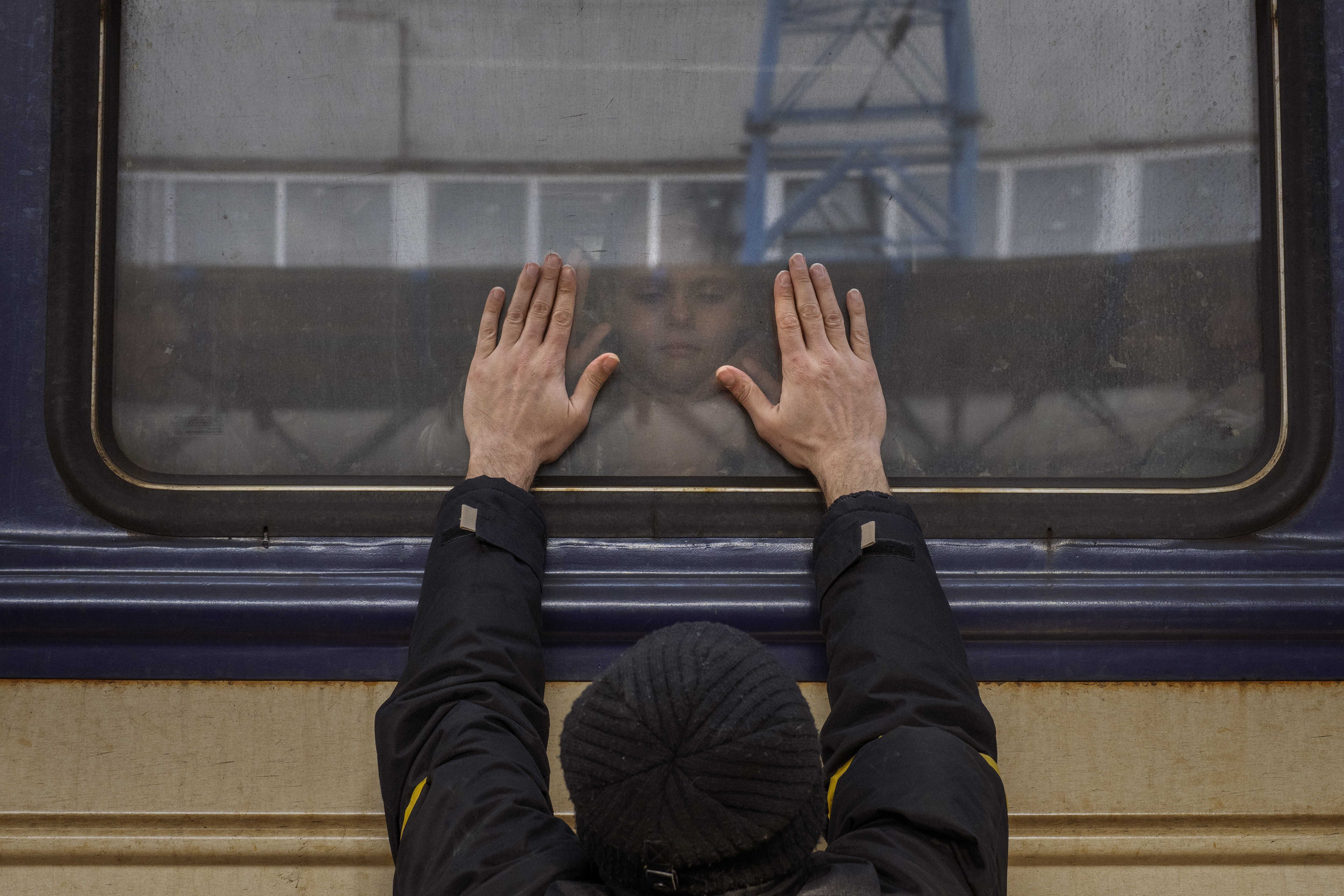 Aleksander, 41, presses his palms against the window as he says goodbye to his daughter Anna, 5, on a train to Lviv at the Kyiv station, Ukraine, Friday. Aleksander has to stay behind to fight in the war while his family leaves the country to seek refuge in a neighboring country.