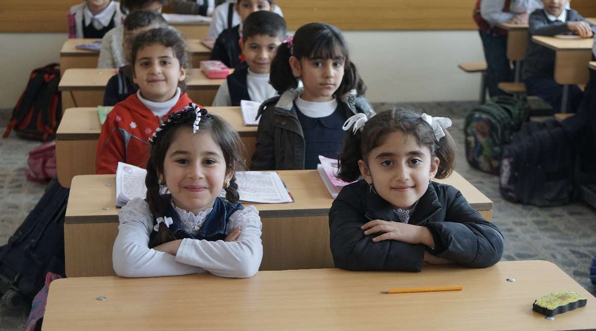 Iraqi students in Mosul smile at desks their parents helped to build at a Christian school with aid from Latter-day Saint Charities. Meaningful work is an important principle in helping those receiving aid after a disaster, said the charity’s president, Sister Sharon Eubank.