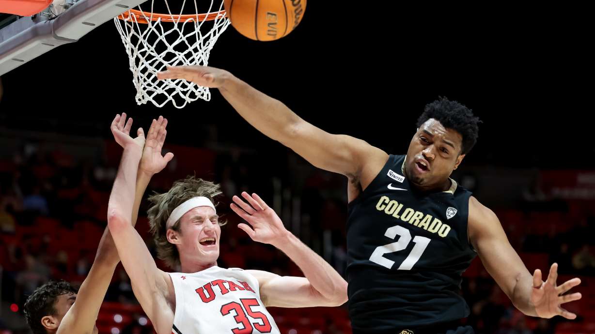 Colorado Buffaloes forward Tristan da Silva (23), left, is charged with a foul as Utah Utes center Branden Carlson (35) goes to the hoop between Silva and Colorado Buffaloes forward Evan Battey (21) during the game at the Huntsman Center in Salt Lake City on Saturday, March 5, 2022.