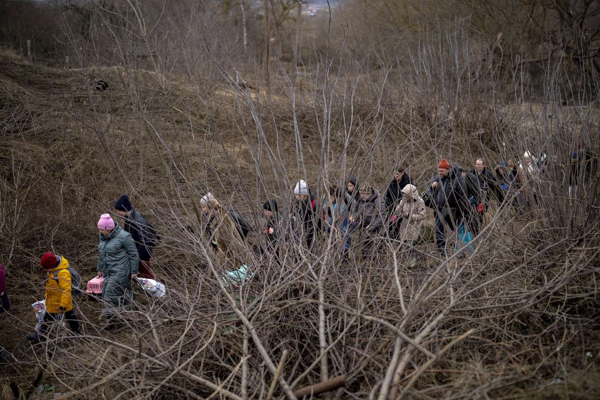 Ukrainian citizens flee crossing the Irpin river in the outskirts of Kyiv, Ukraine, Saturday.