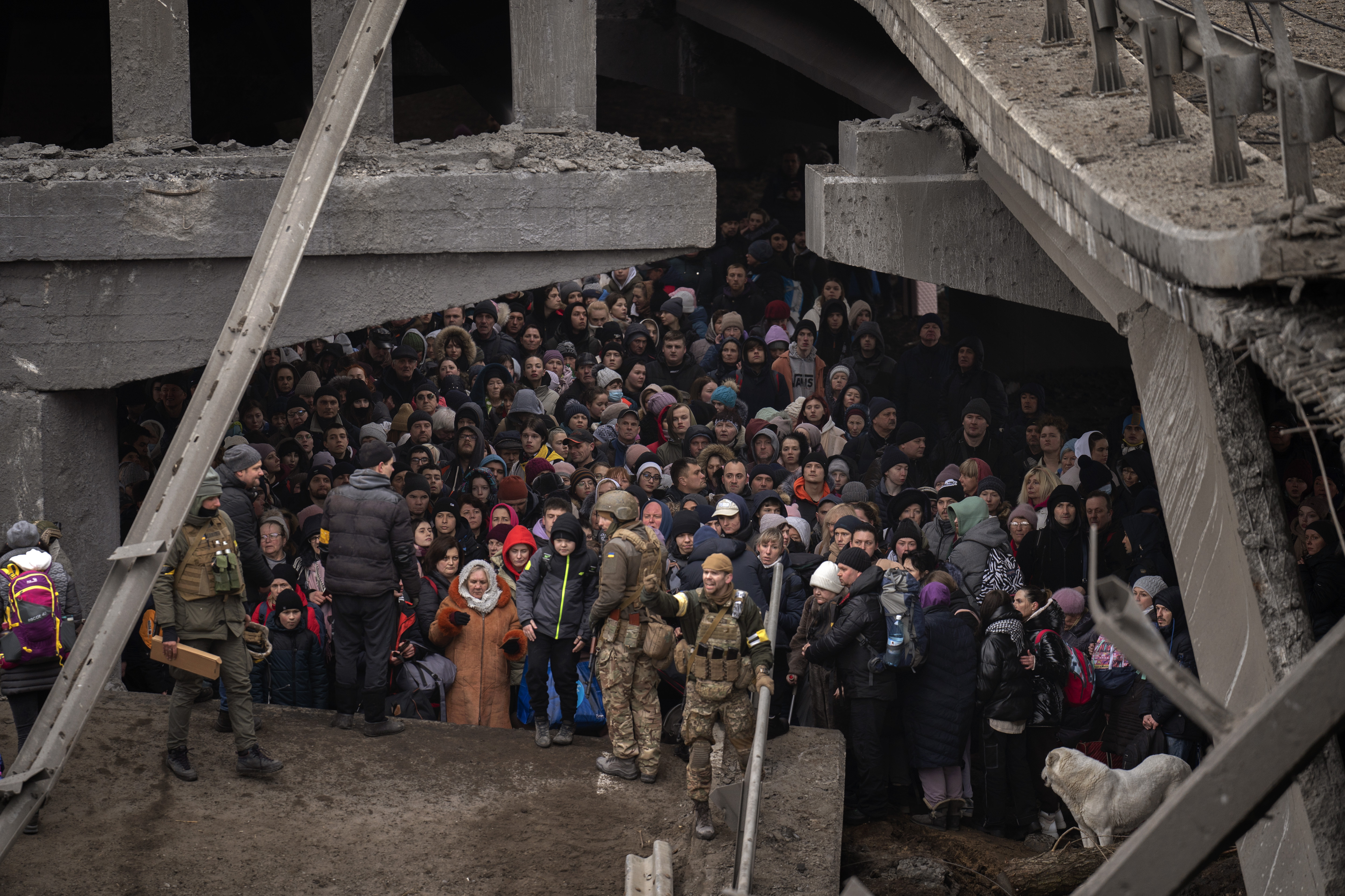 Ukrainians crowd under a destroyed bridge as they try to flee crossing the Irpin river in the outskirts of Kyiv, Ukraine, Saturday.