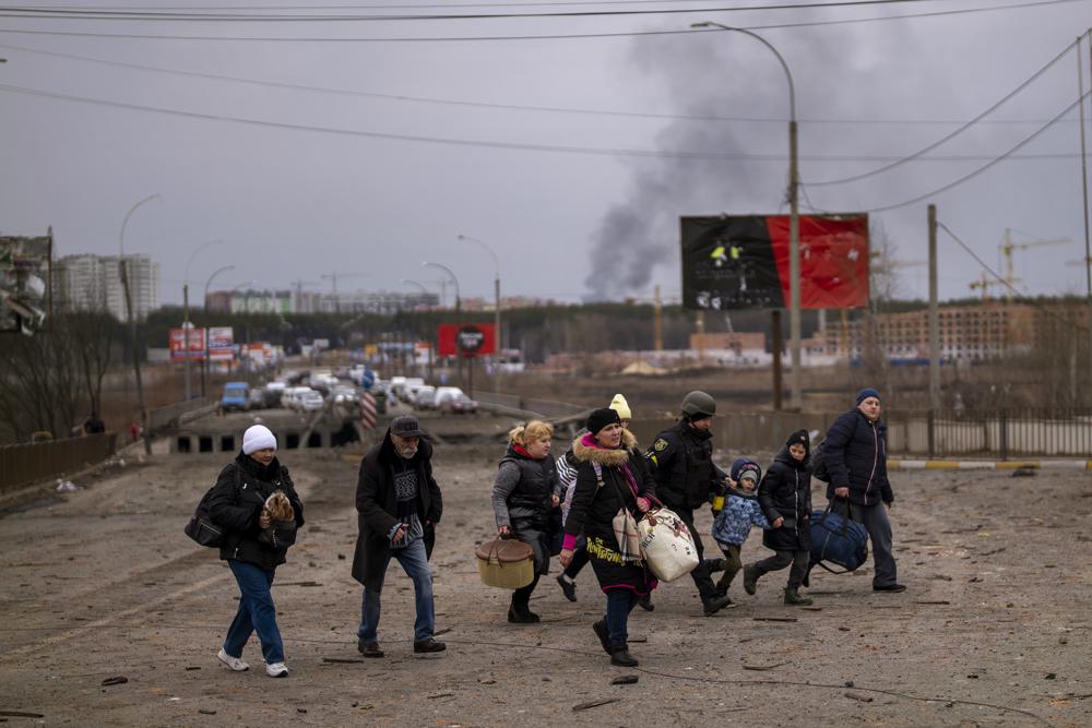 A Ukrainian police officer helps people as artillery echoes nearby while fleeing Irpin in the outskirts of Kyiv, Ukraine, Monday. Russia announced yet another cease-fire and a handful of humanitarian corridors to allow civilians to flee Ukraine. Previous such measures have fallen apart and Moscow’s armed forces continued to pummel some Ukrainian cities with rockets Monday.