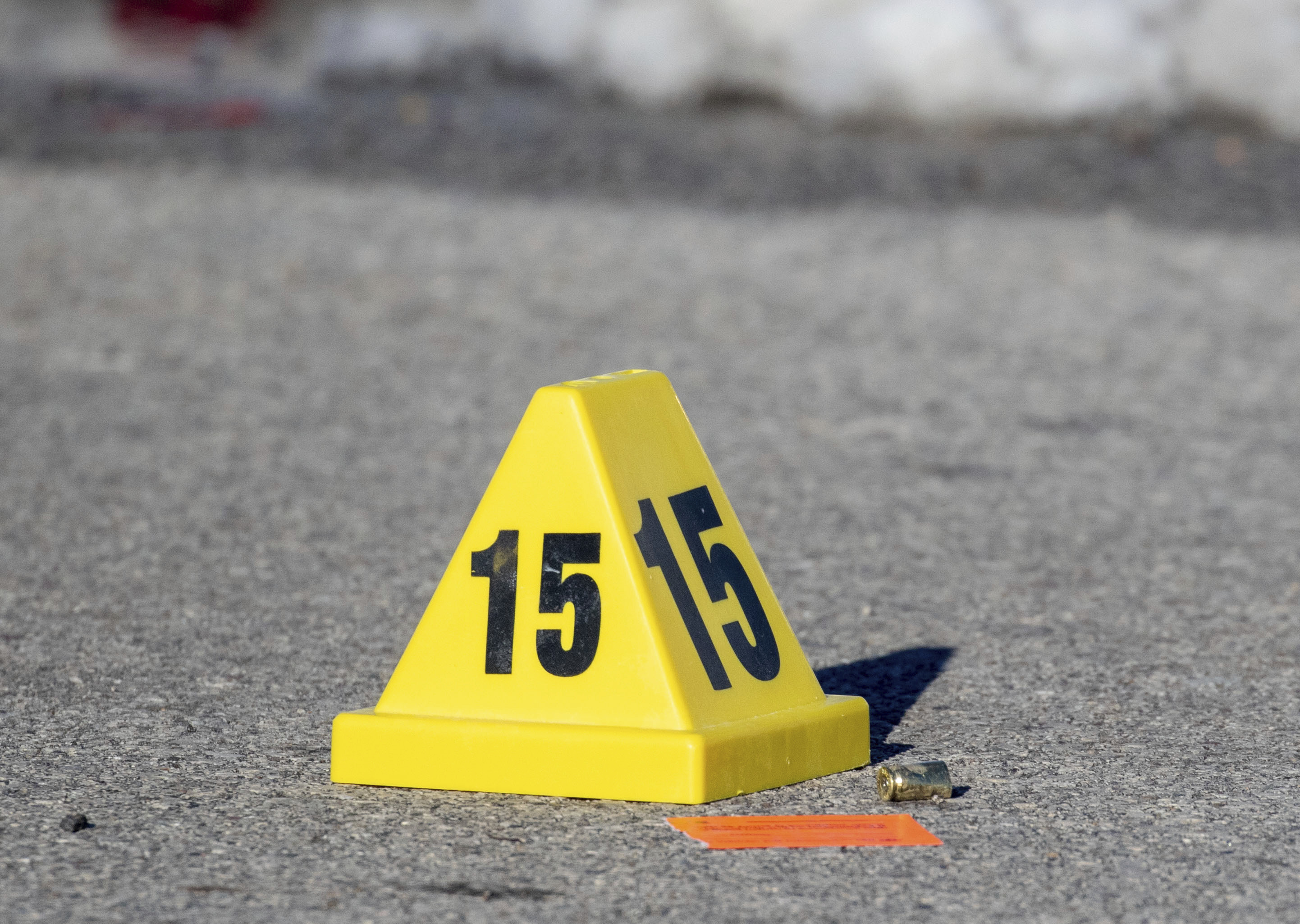 An evidence marker lies next to a bullet casing as police investigate a shooting outside of East High School in in Des Moines, Iowa, on Monday, March 7.