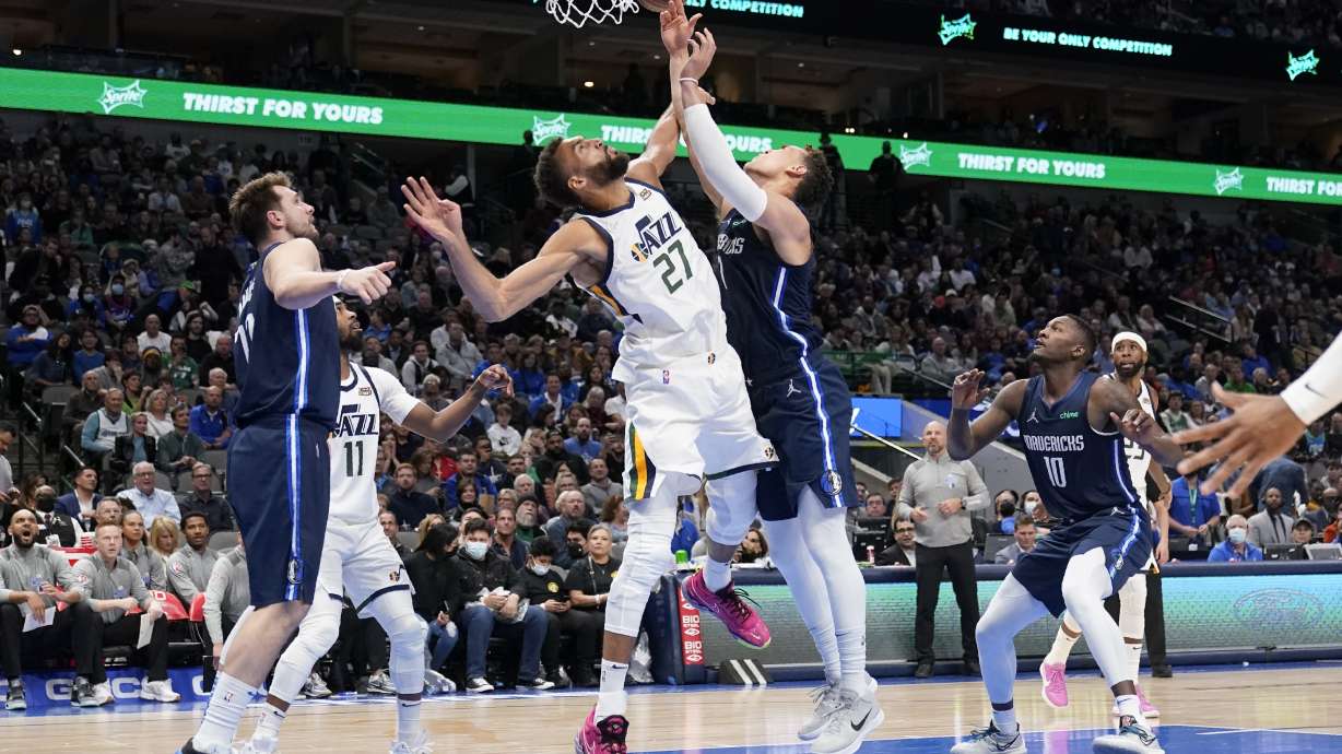 Utah Jazz center Rudy Gobert (27) blocks a shot-attempt by Dallas Mavericks center Dwight Powell, right, as Mavericks' Luka Doncic, left, looks on in the second half of an NBA basketball game in Dallas, Monday, March, 7, 2022.