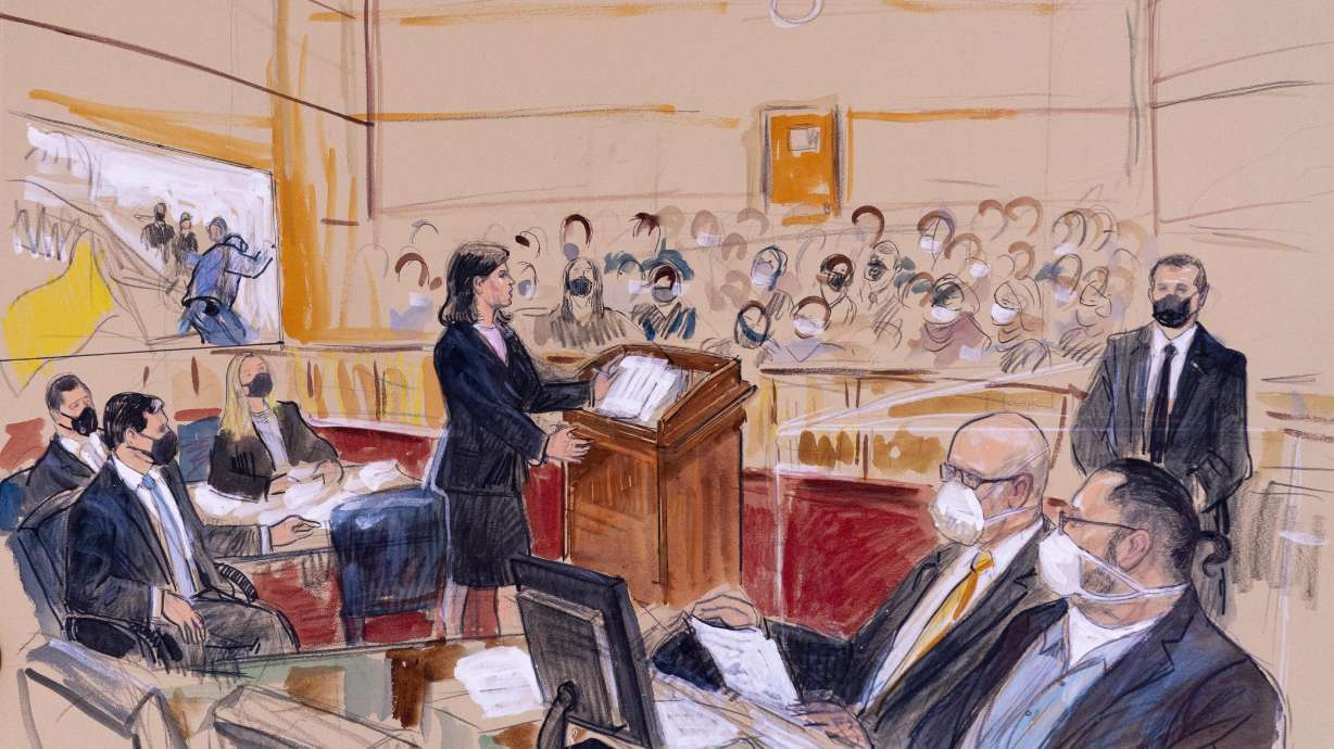 This artist sketch depicts Guy Wesley Reffitt, bottom right, joined by his lawyer William Welch, third from right, listening as prosecutor Risa Berkower, speaks at the podium at center, as a video depicts a handgun on the waist of Reffitt, at left, for members of the jury and audience in Federal Court, in Washington, Monday. Reffitt, a Texas man charged with storming the U.S. Capitol with a holstered handgun on his waist, is the first Jan. 6 defendant to go on trial.