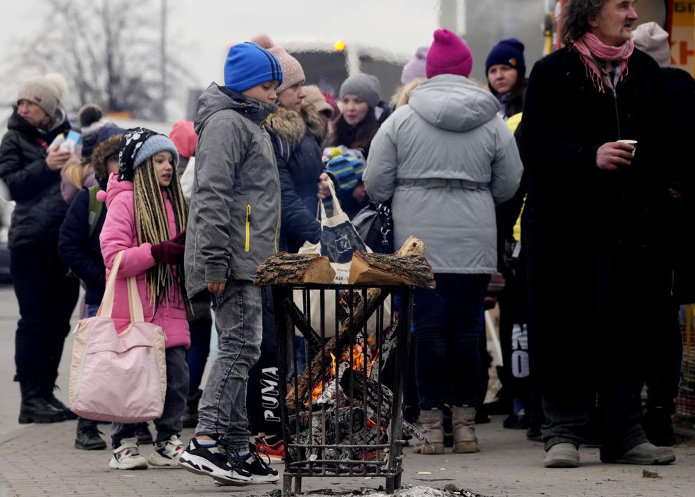 Children warm up around a fire as they arrive in a humanitarian aid center, for displaced persons fleeing Ukraine, in Przemysl, Poland, Tuesday. U.N. officials said Tuesday that the Russian onslaught has forced more than 2 million people to flee Ukraine.