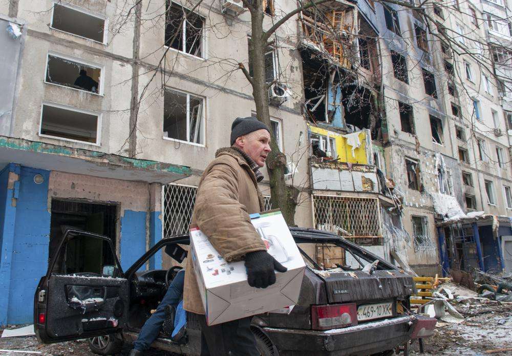 A man carries belongings out of an apartment building hit by shelling in Kharkiv, Ukraine, Tuesday.