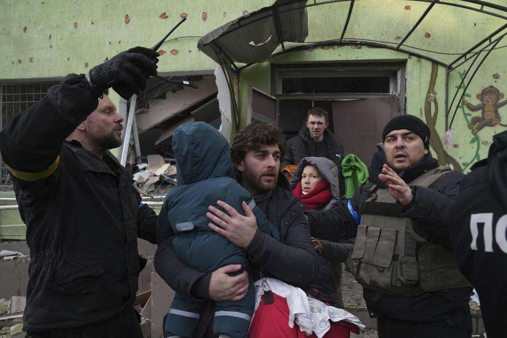 A man carries his child away from the damaged by shelling maternity hospital in Mariupol, Ukraine, Wednesda. A Russian attack has severely damaged a maternity hospital in the besieged port city of Mariupol, Ukrainian officials say.