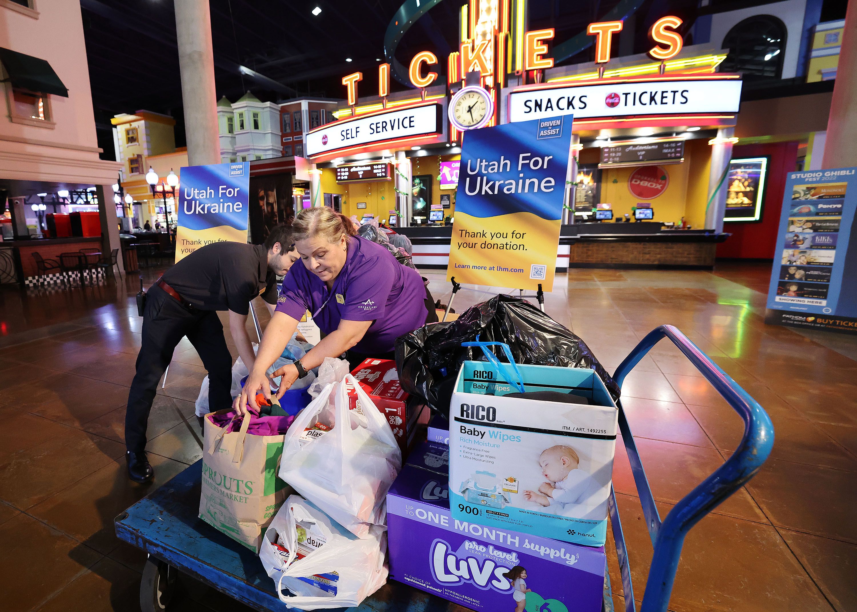 Jill Griggs and Weston Karren on Wednesday, move donations for Ukrainian refugees that have been dropped off at the Larry H. Miller Megaplex Theatres at Jordan Commons in Sandy.