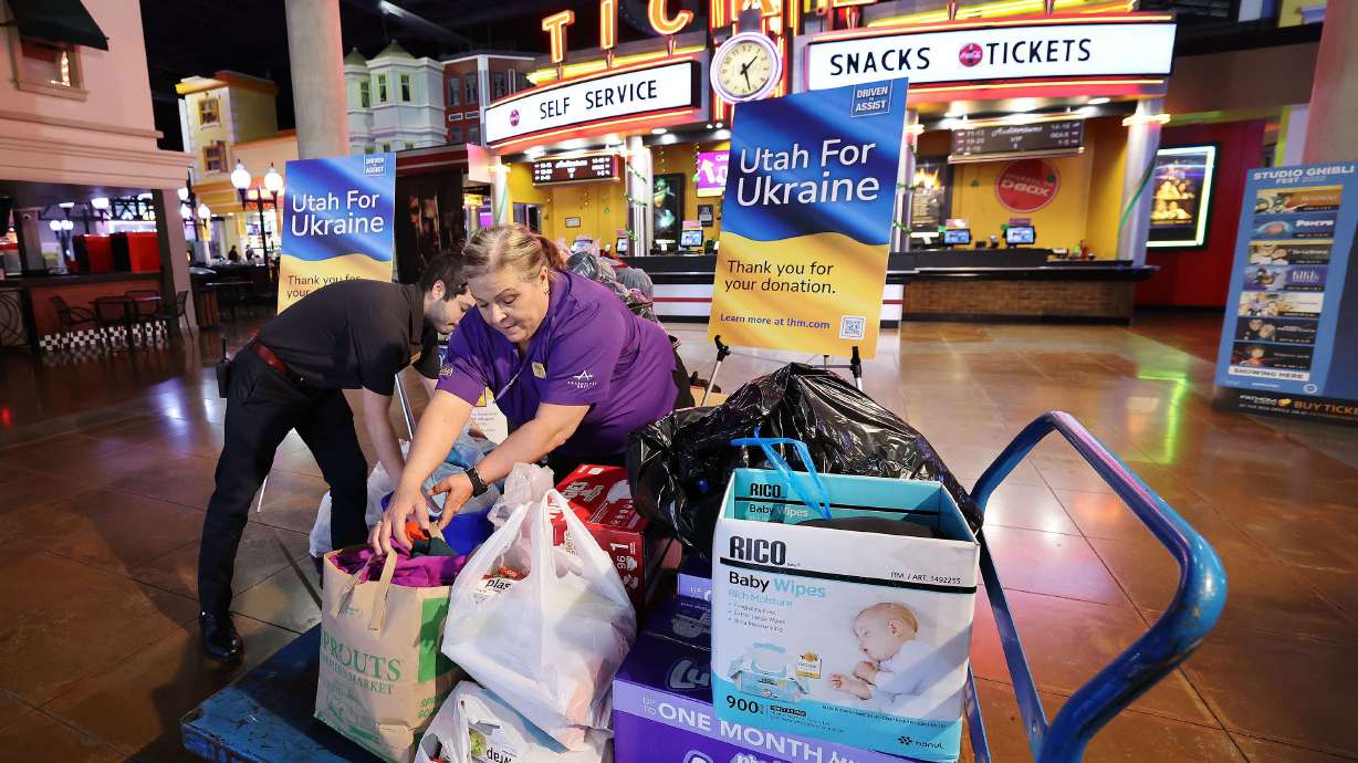 Jill Griggs and Weston Karren on Wednesday, move donations for Ukrainian refugees that have been dropped off at the Larry H. Miller Megaplex Theatres at Jordan Commons in Sandy.