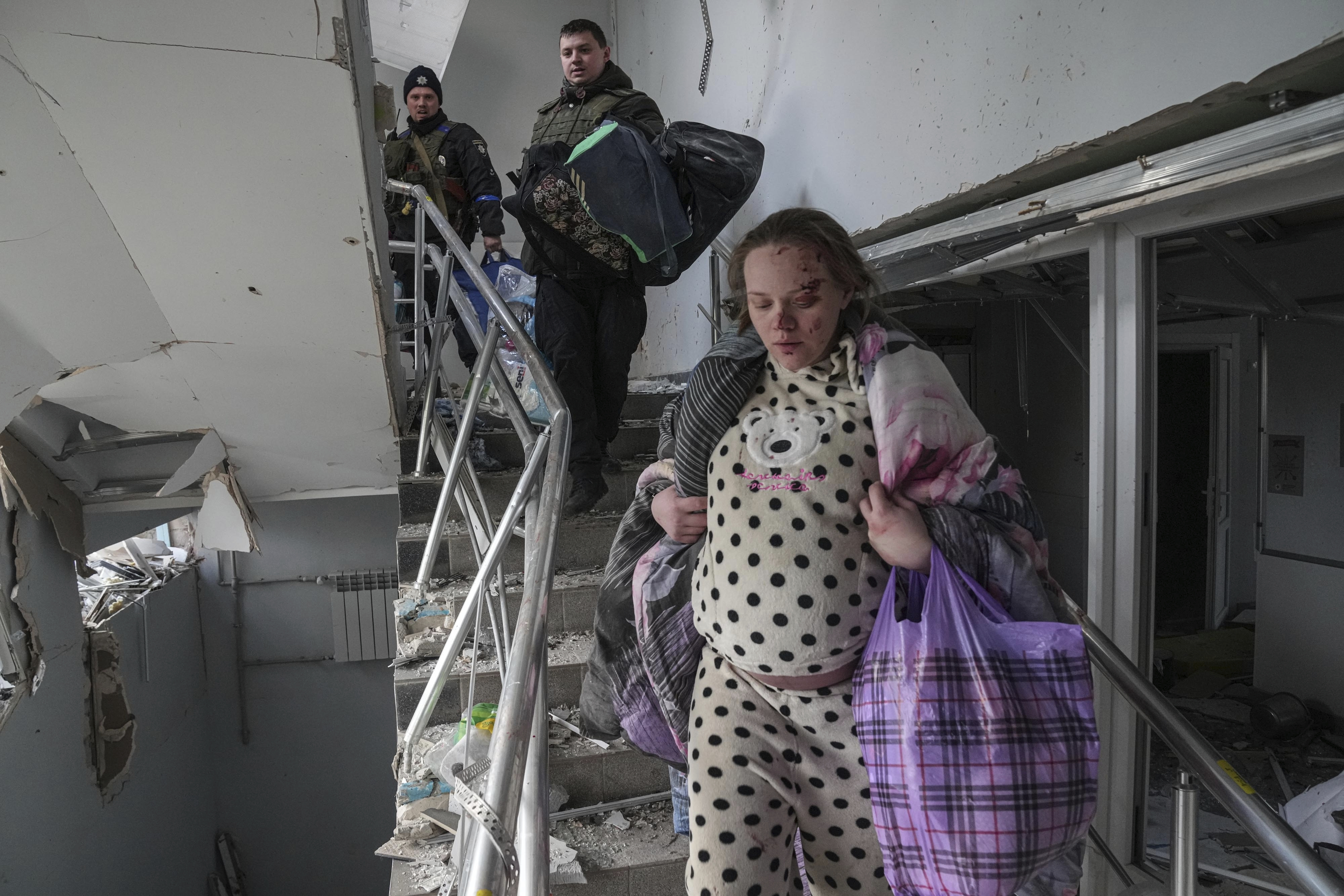 An injured pregnant woman walks downstairs in the damaged by shelling maternity hospital in Mariupol, Ukraine, Wednesday. A Russian attack has severely damaged a maternity hospital in the besieged port city of Mariupol, Ukrainian officials say.