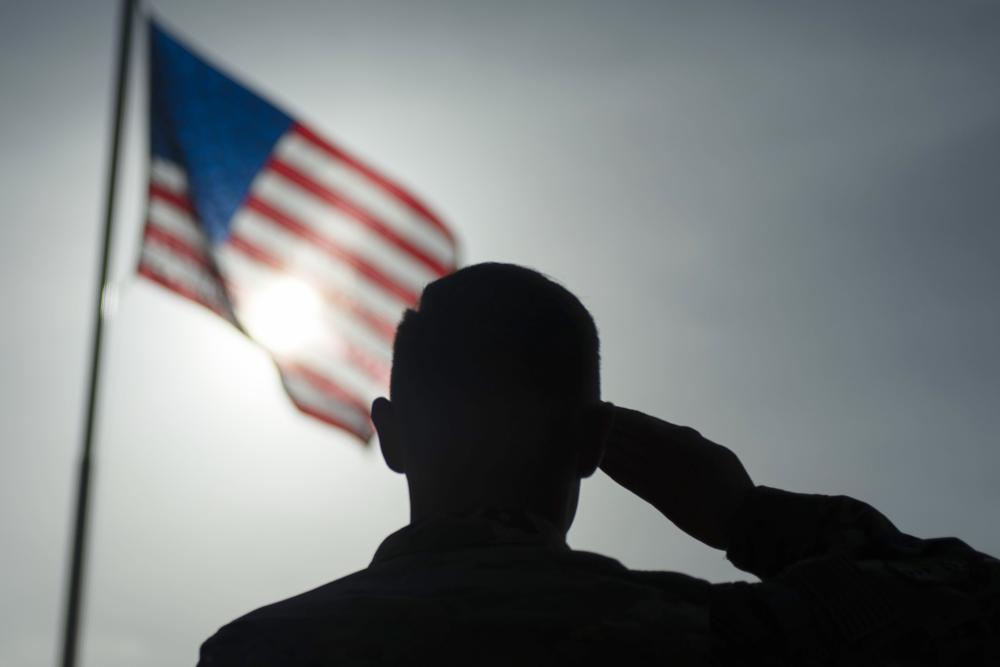 A U.S. Air Force sergeant salutes the flag during a ceremony at Camp Simba, Manda Bay, Kenya, in August 2019. Military investigations have found poor leadership, inadequate training and a "culture of complacency” among U.S. forces undermined efforts to fend off a 2020 attack by militants in Kenya that killed three Americans. 
