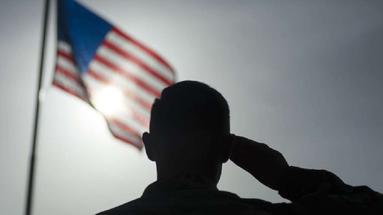 A U.S. Air Force sergeant salutes the flag during a ceremony at Camp Simba, Manda Bay, Kenya, in August 2019. Military investigations have found poor leadership, inadequate training and a "culture of complacency” among U.S. forces undermined efforts to fend off a 2020 attack by militants in Kenya that killed three Americans.